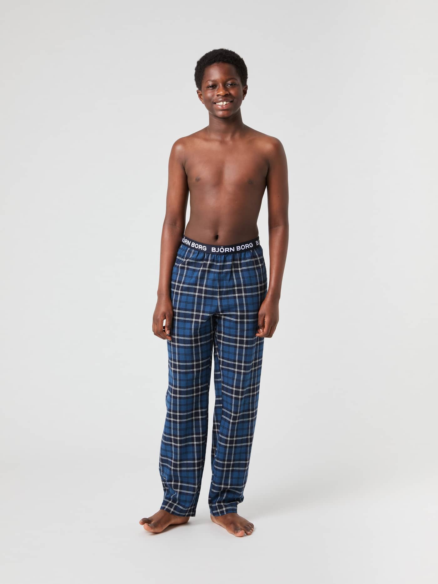 Boy model seen from the front, wearing the Björn Borg Core Flannel Pyjama Pants in a blue tartan pattern. - Image 3
