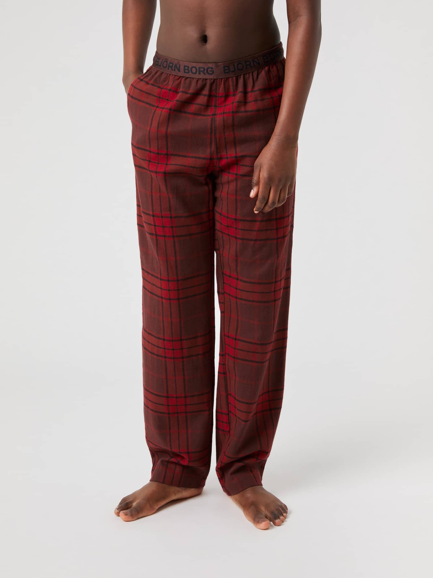 Front view of a model wearing Björn Borg Core Flannel Pyjama Pants in a red and brown tartan print. - Image 1