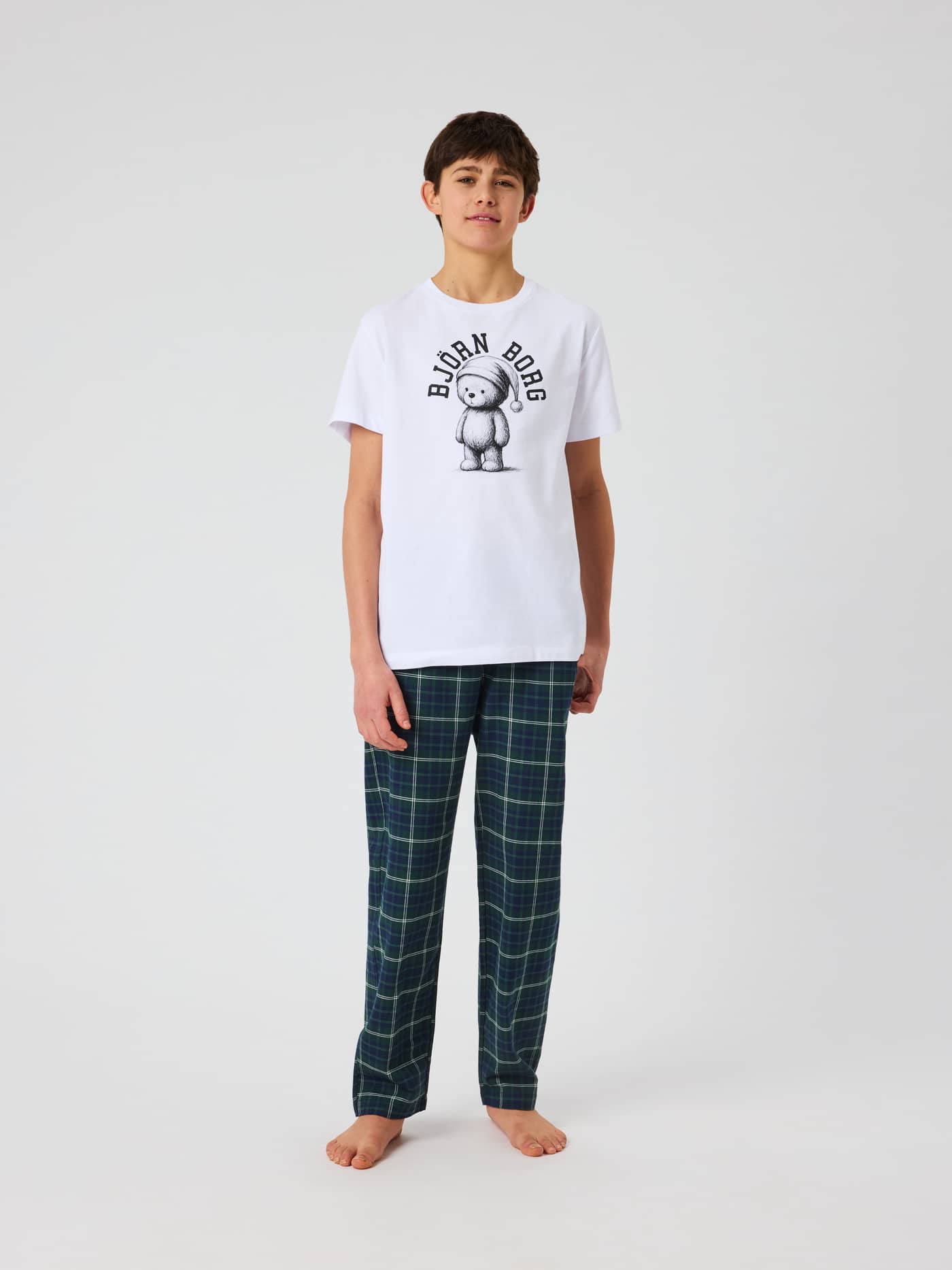 Front view of a kid wearing Core Pyjama Pants with a tartan check pattern. - Image 1