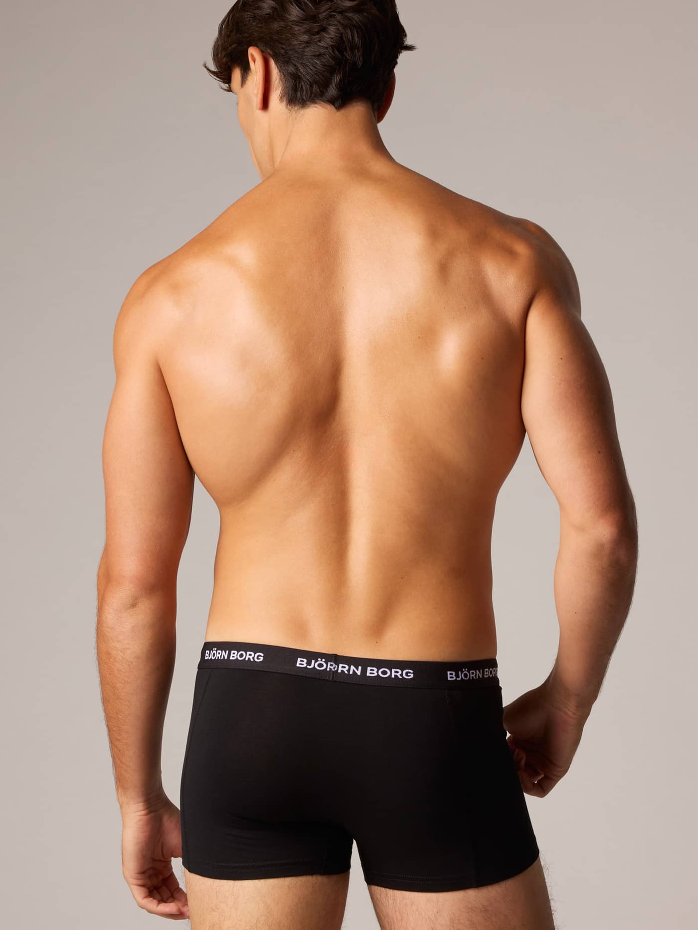 Back view of a man wearing the black Cotton Stretch Trunks 5-pack, with a white logo waistband for style and a perfect fit. - Image 2