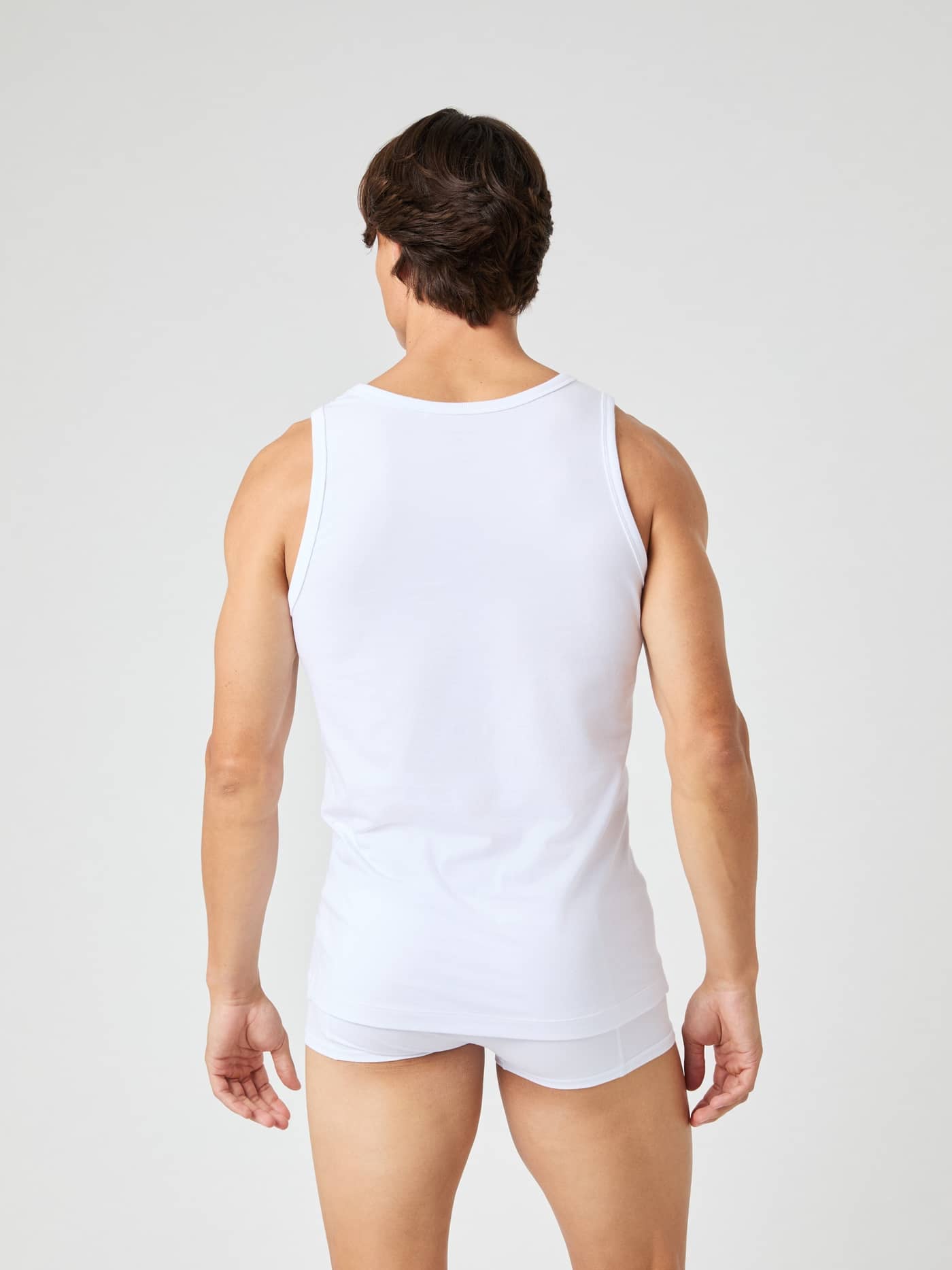 Back view of a man wearing the Björn Borg Core Slim Tank 2-pack in Brilliant White (White) for a modern slim fit. - Image 3