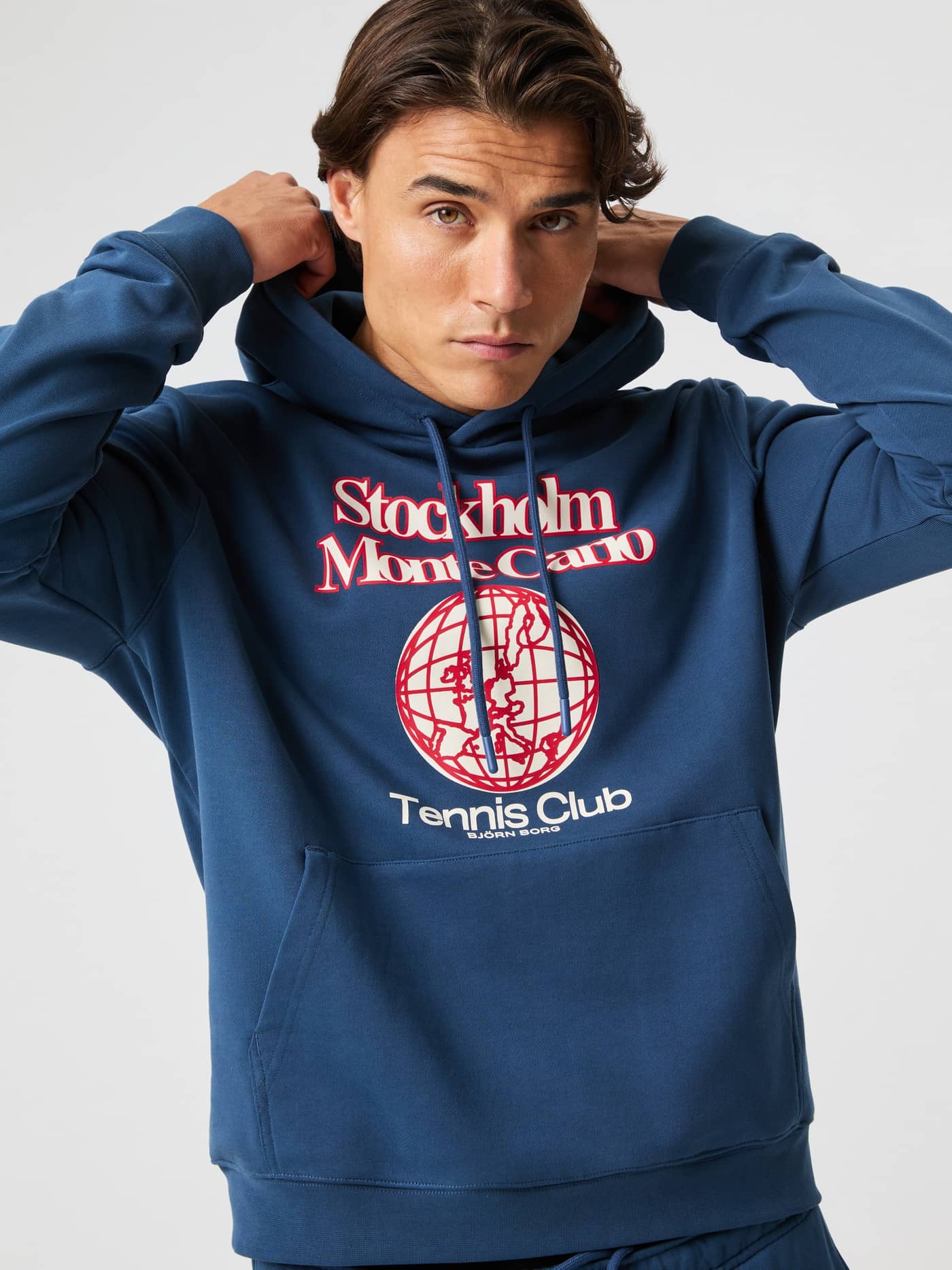 Front view of a man in the Sargasso Sea (Blue) cotton Björn Borg Classic Print Hoodie with a red tennis graphic. - Image 5