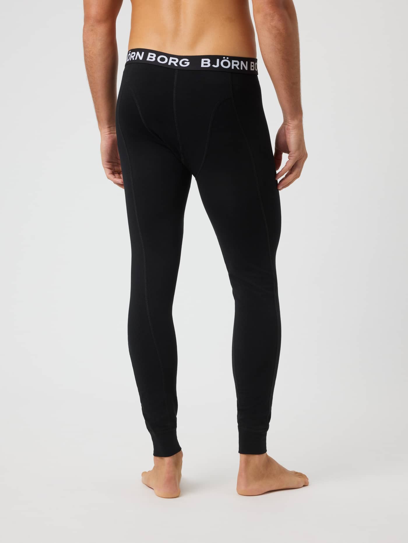 Back view of a man wearing the black Cotton Stretch Long Johns 1-pack, featuring a white logo waistband. - Image 3