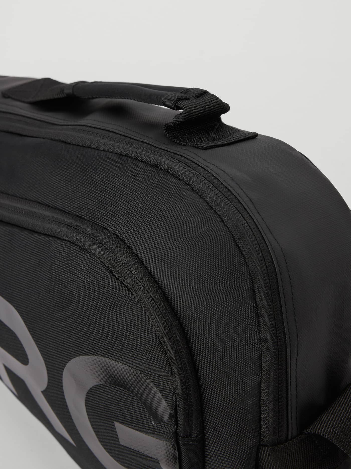 Primer plano del asa, la cremallera y el logotipo negro de la Ace Padel Bag S - 10 L en Black Beauty (Negro) para tenis. - Image 3