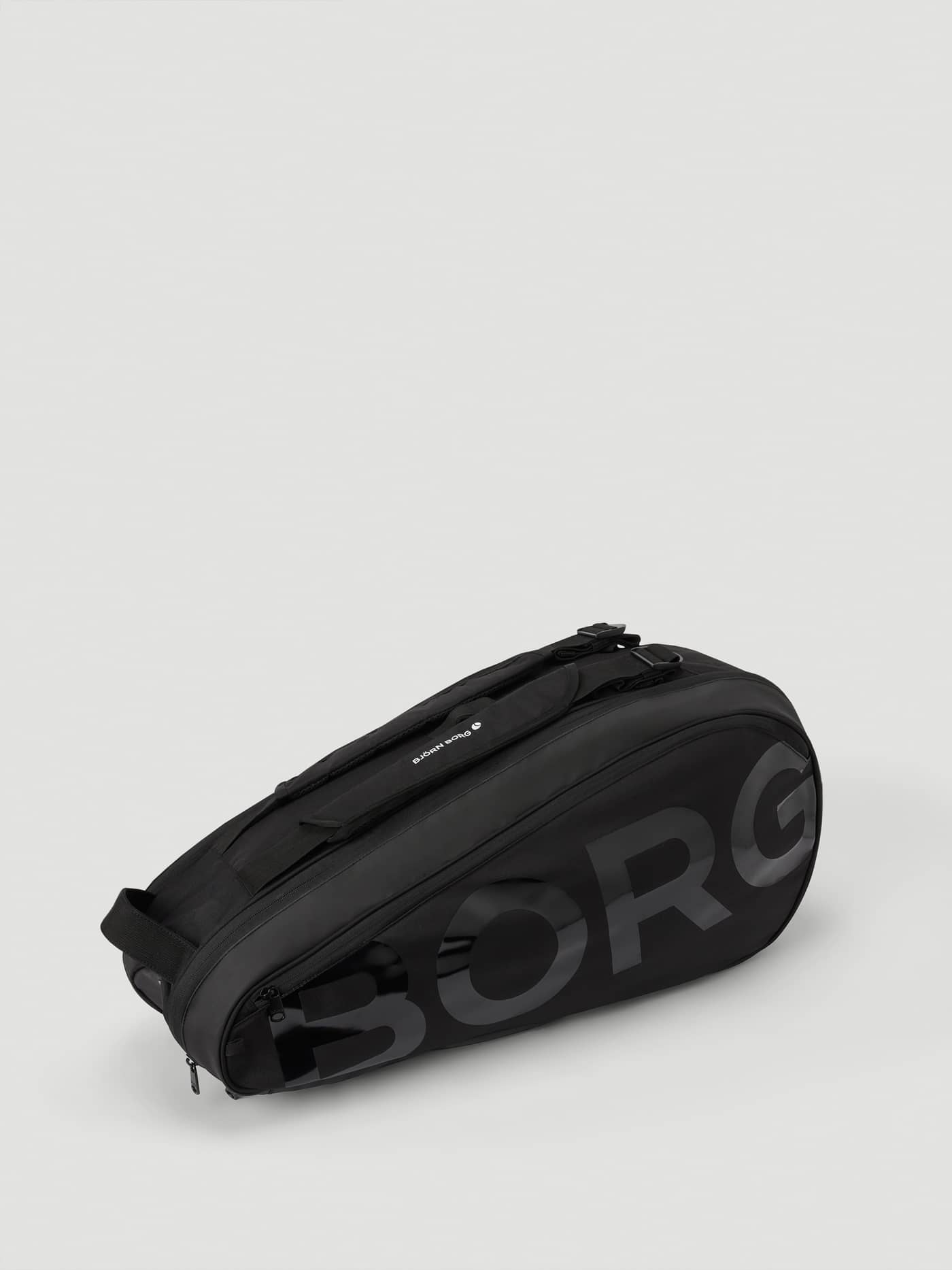 Ace Tennis Bag i Black Beauty (Sort) set fra siden med et stort tone-i-tone logo på slidstærk polyester. - Image 3