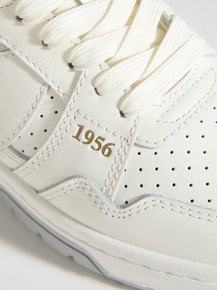 Close-up van de witte Men's Ollie Leather Sneakers van rundleer met geperforeerde tennisstijl en gouden 1956. - Image 5