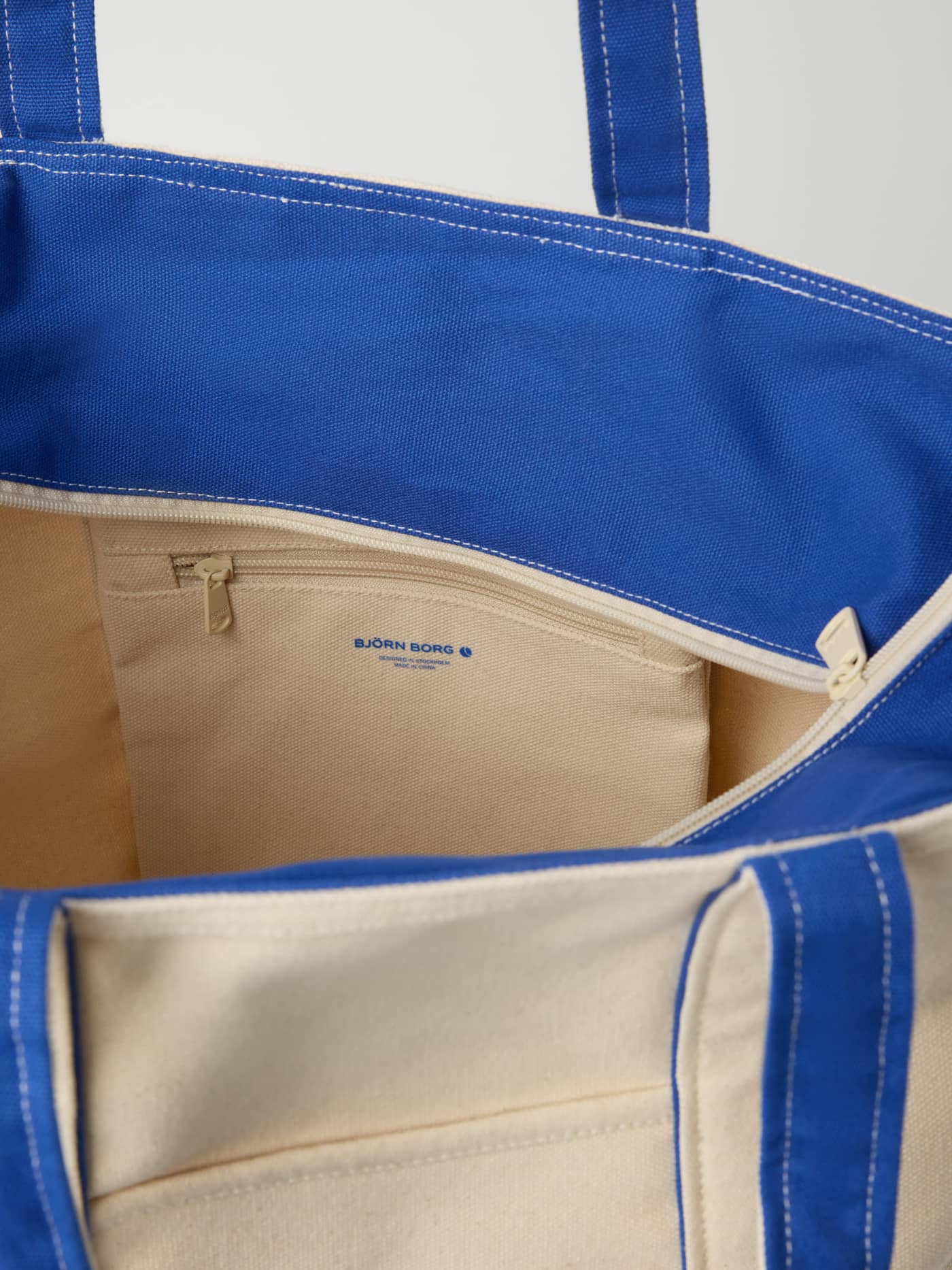Innsiden av Ace Canvas Tote 30L i bomull, Egret (Hvit) med glidelåslomme og blå detaljer til tennis. - Image 3