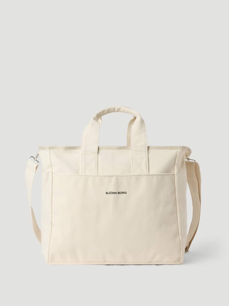 Vue de face du Studio Canvas Tote 34L en Egret (Blanc), en 100 % coton avec un logo noir. - Image 1