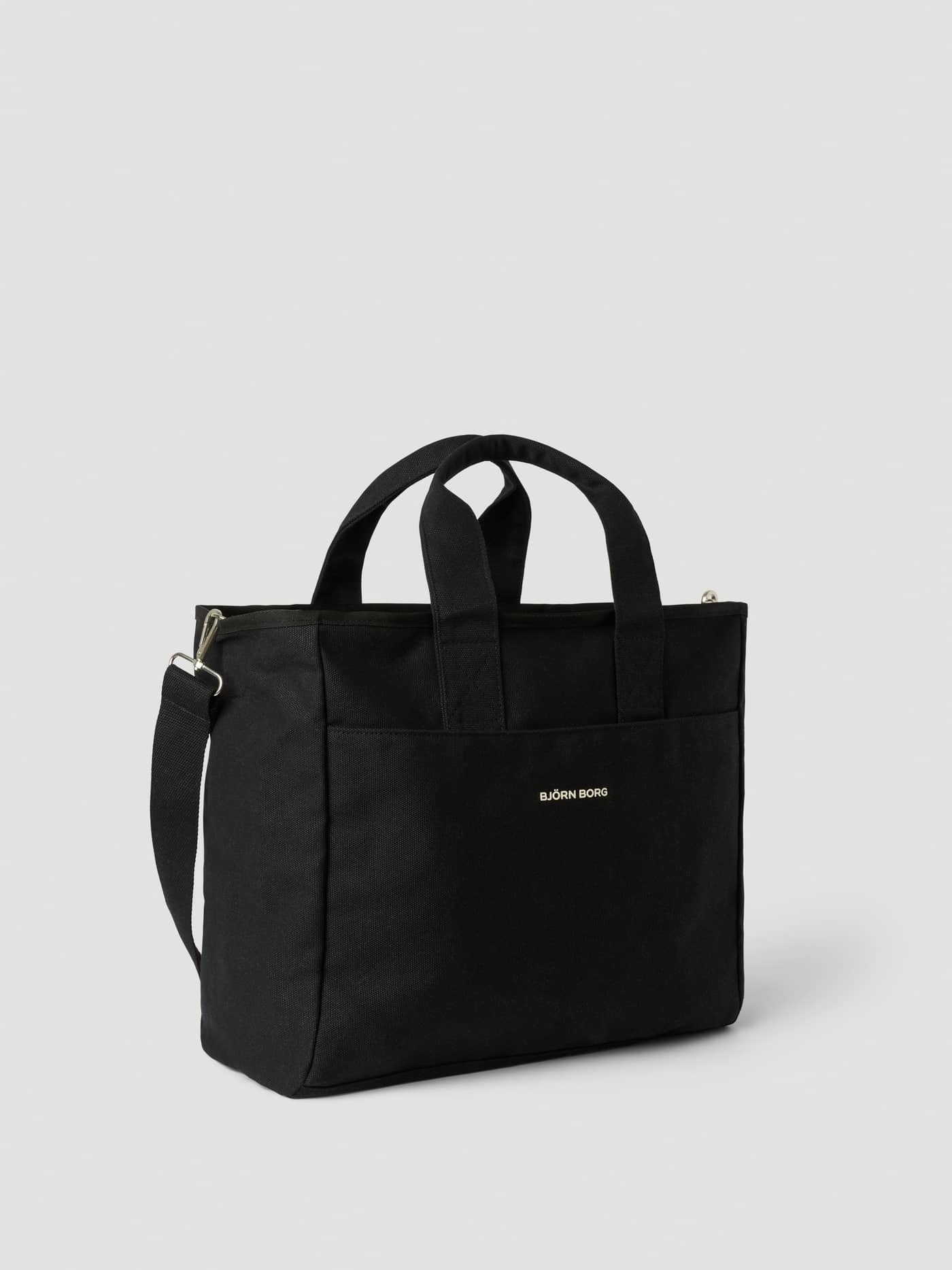 Studio Canvas Tote 34L in Black Beauty (Zwart) van katoenen canvas met een wit logo en schouderband. - Image 2