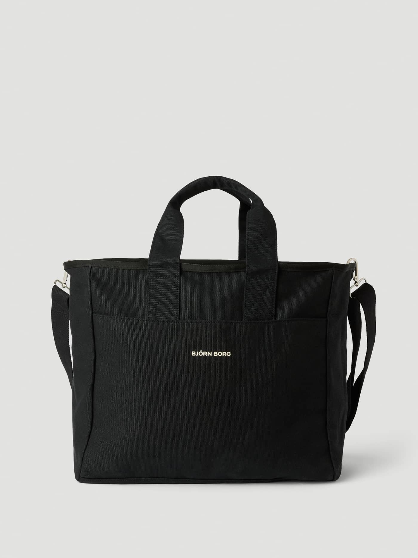 Studio Canvas Tote 34L in Black Beauty (Zwart), een katoenen canvastas met handvatten en een wit logo, vooraanzicht. - Image 1
