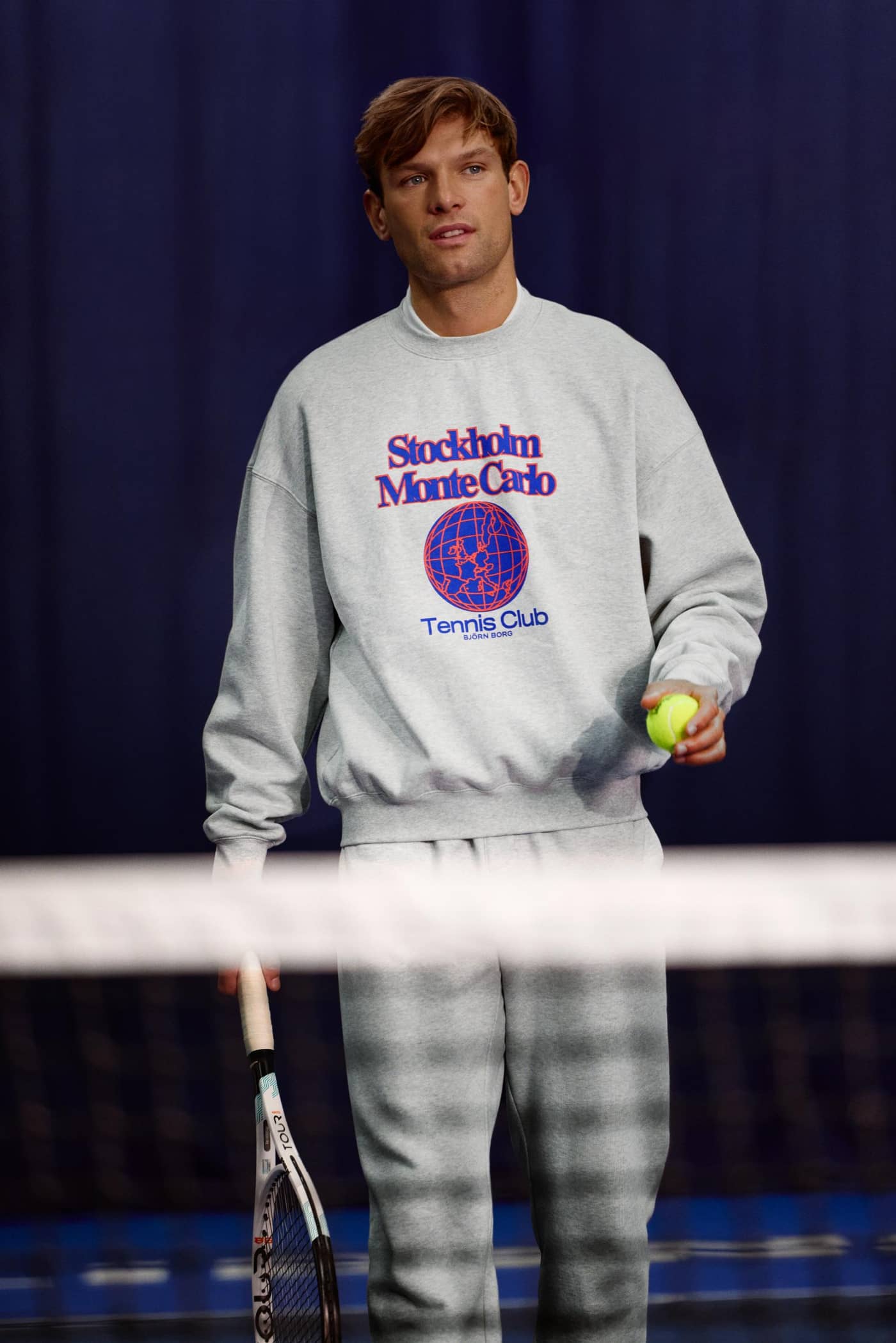 BORG OVERSIZED SWEATSHIRT i Grey (Grå) set forfra på en tennisbane med et rødt og blåt tennislogo. - Image 2