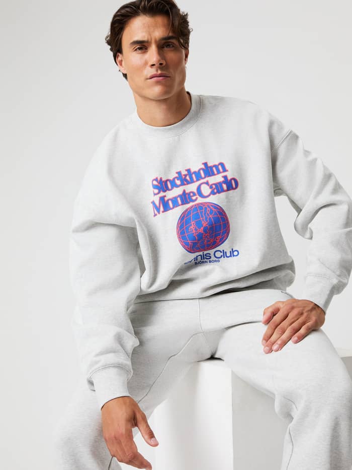 Front view of a man in the Ultra Light Grey Melange (Grey) Borg Oversized Sweatshirt with a red and blue tennis print.
