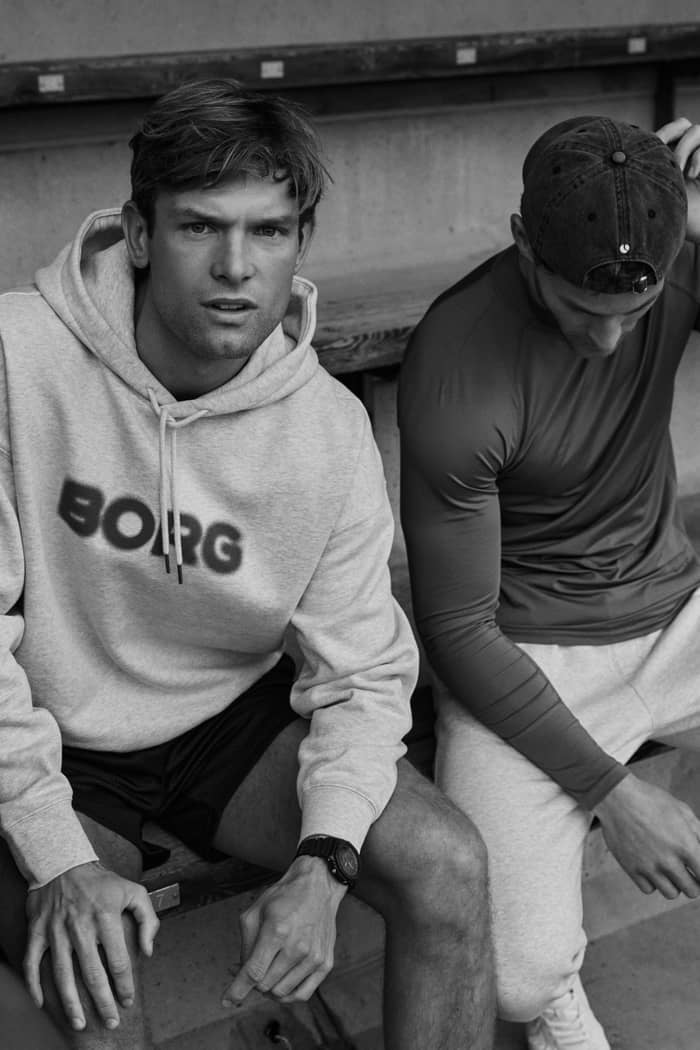Man wearing the Borg Oversized Hoodie in Ultra Light Grey Melange (Grey) with a soft cotton blend and blurred dark logo.