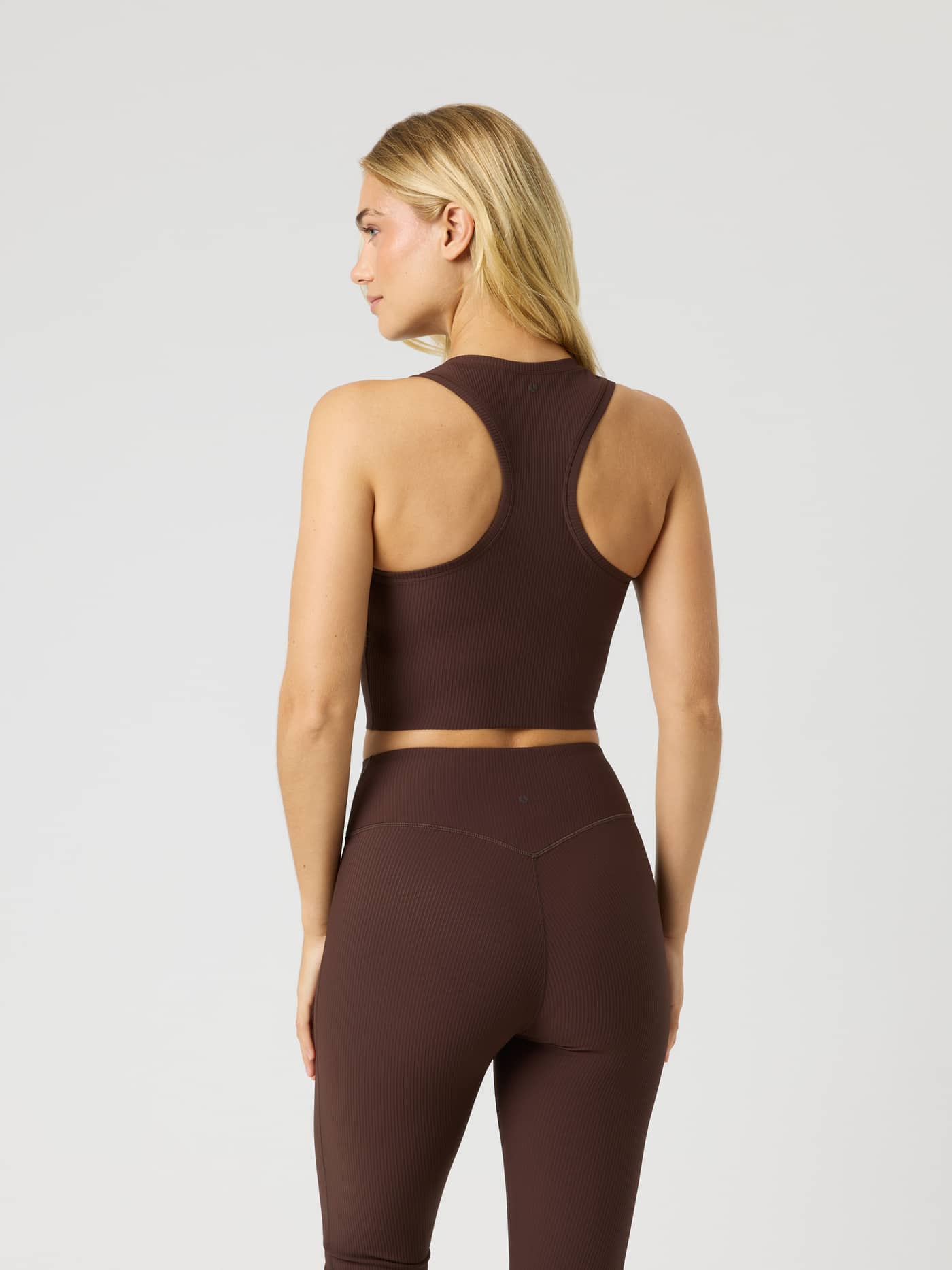 Back view of the Studio Ribbed Cropped Tank Top in Coffee Bean (Brown) with a ribbed texture and brown logo for training. - Image 4
