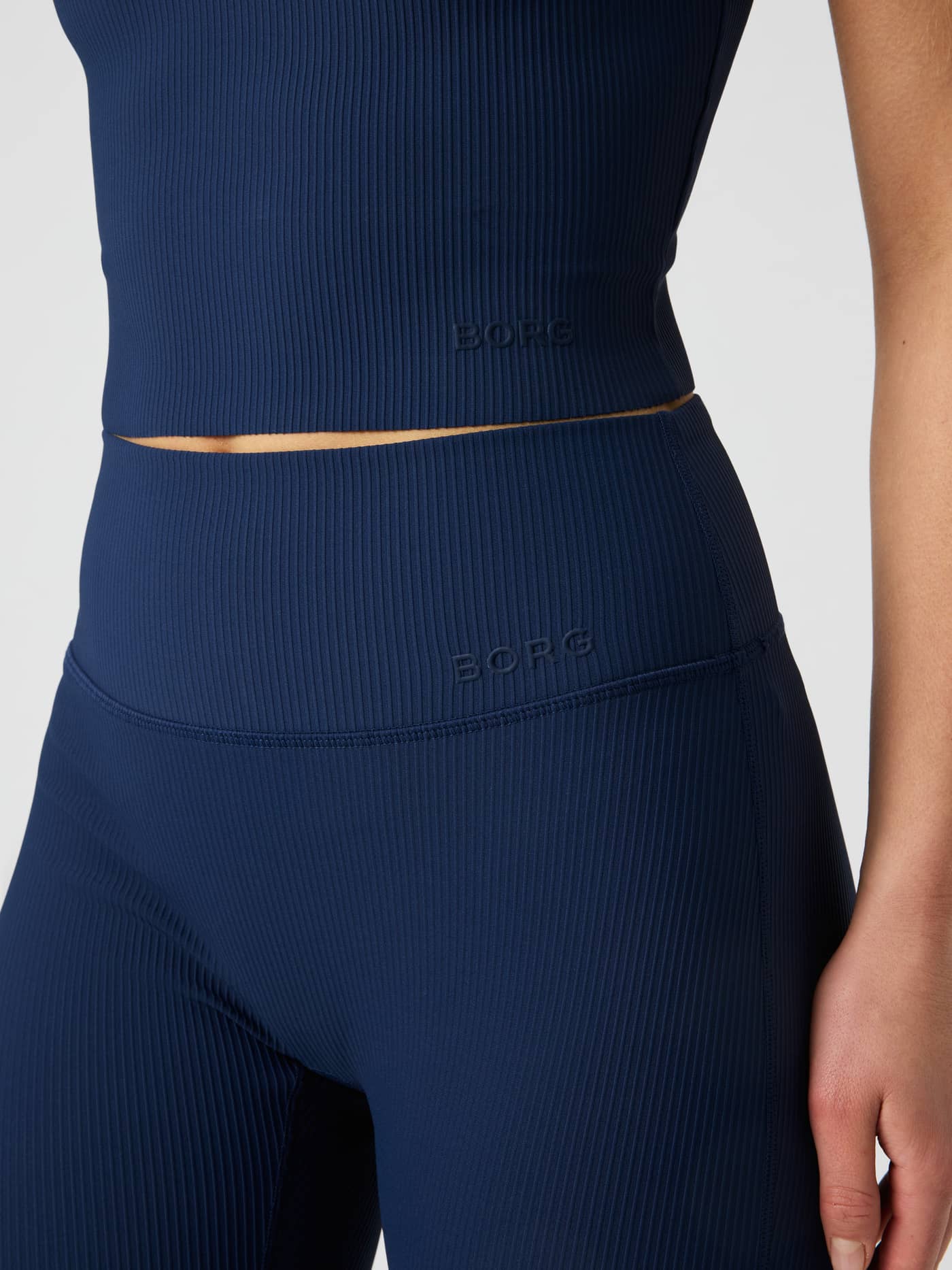 Närbild på Studio Ribbed Cropped Tank Top i dress blues (marinblå) med ribbad struktur och tonal logotyp. - Image 5