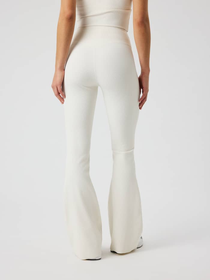 Achteraanzicht van de Studio Ribbed Flare Tights Regular in Tofu (Wit) met een geribde stof en uitlopende trainingspijpen. - Image 3
