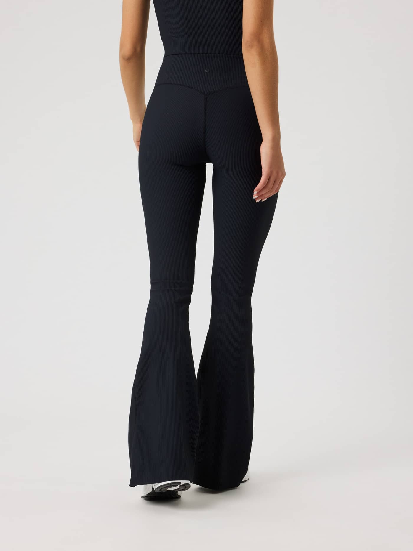 Back view of the Studio Ribbed Flare Tights Regular in Black Beauty (Black), highlighting a stylish flared fit for training. - Image 4