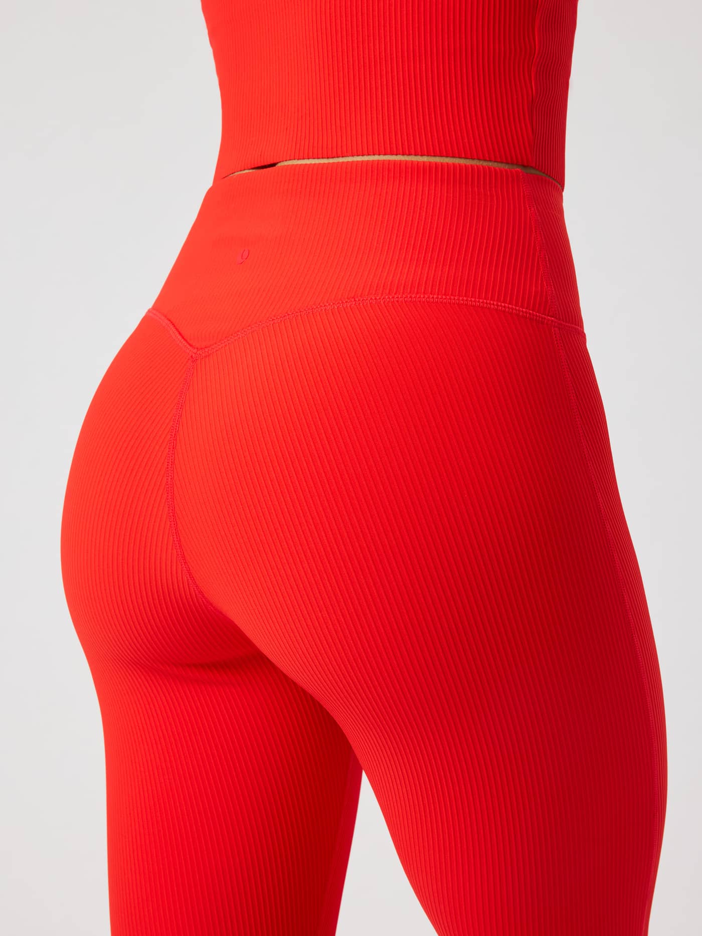Back view of Studio Ribbed Flare Tights Regular in Flame Scarlet (Red) with a ribbed texture and red logo for training. - Image 4