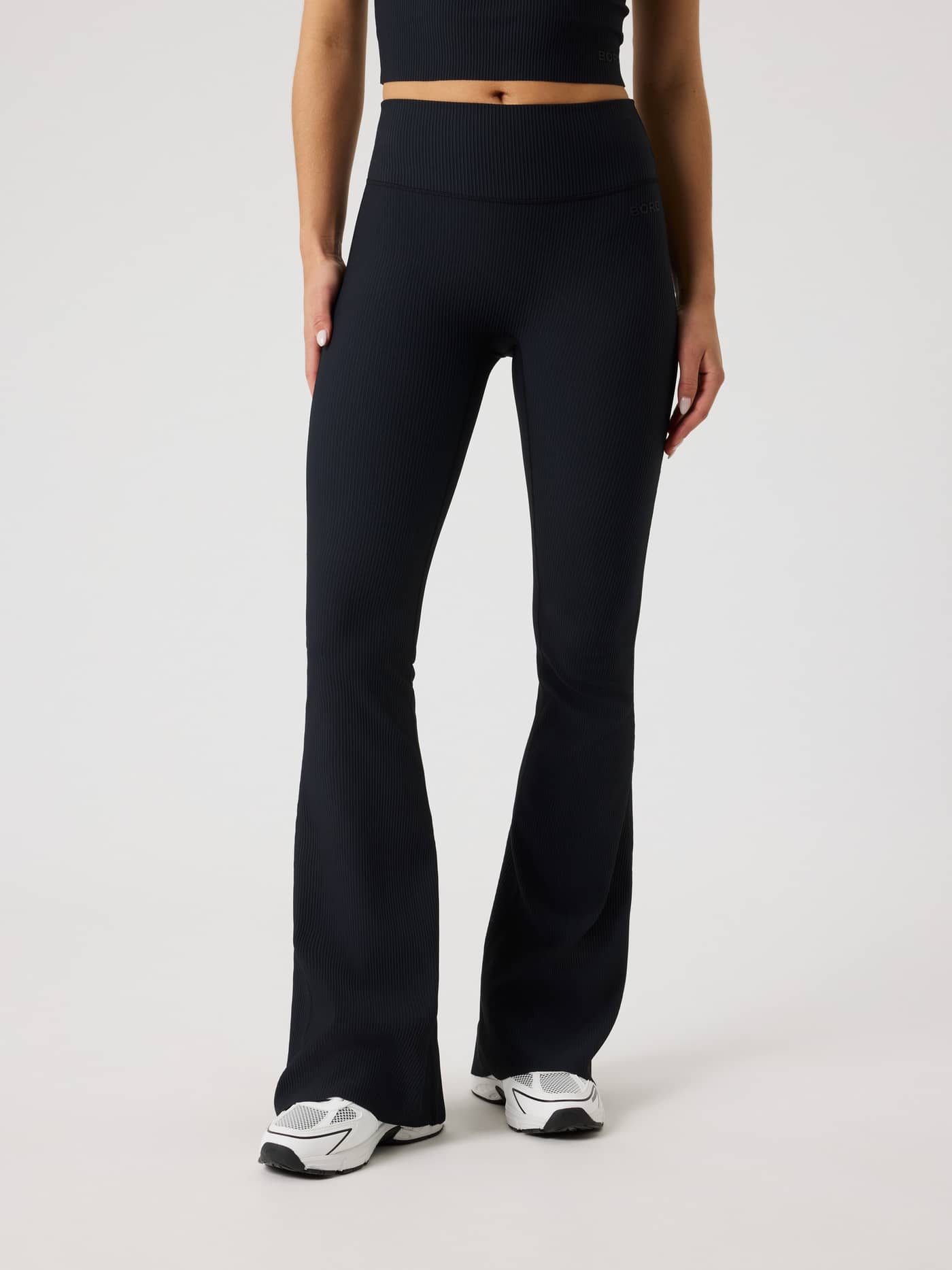 Front view of a woman wearing the Studio Ribbed Flare Tights Regular in Black Beauty (Black) for training. - Image 3