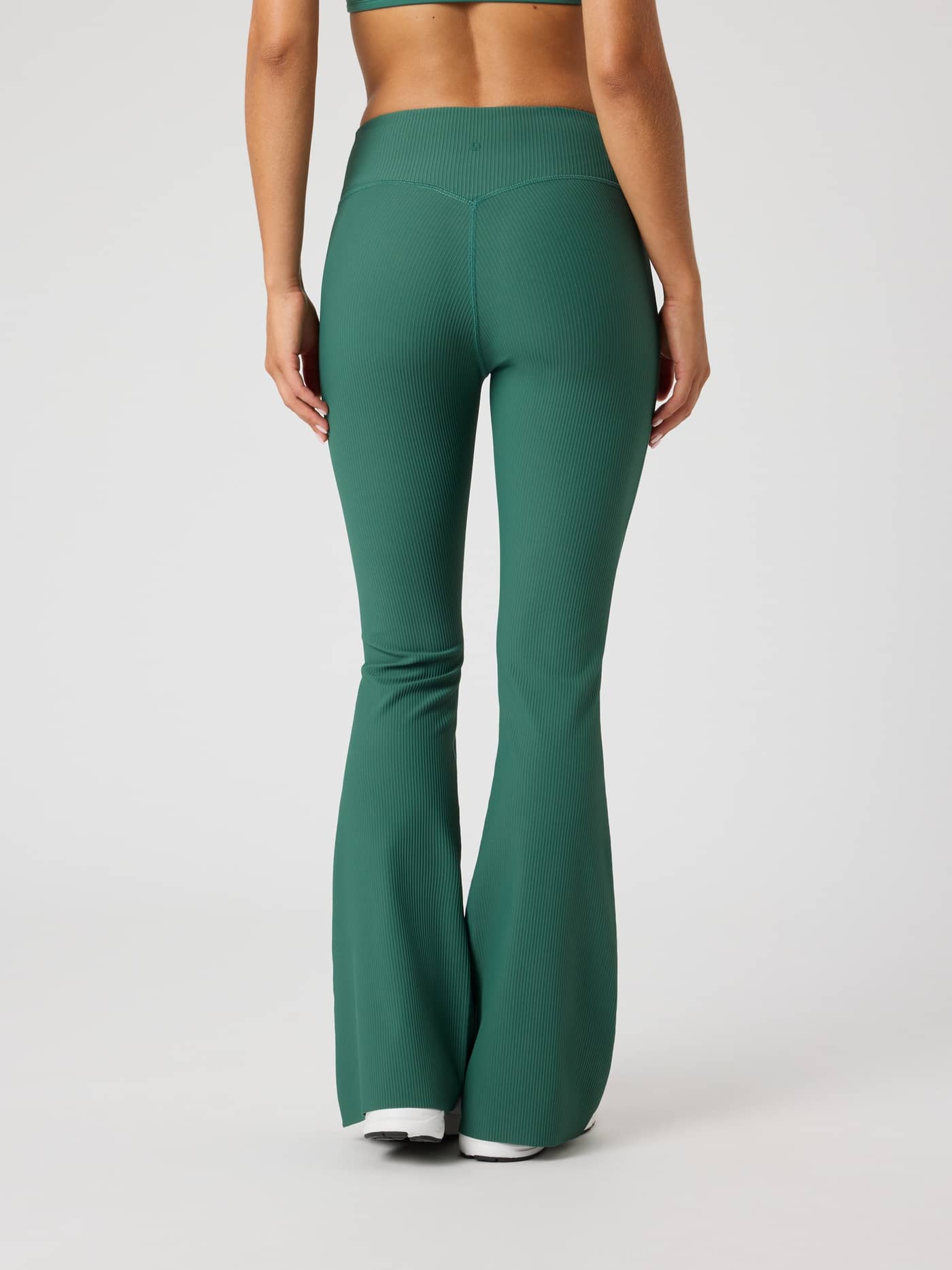 Back view of a woman wearing Mallard Green (Green) Studio Ribbed Flare Tights Regular with a tonal logo for a training fit. - Image 2