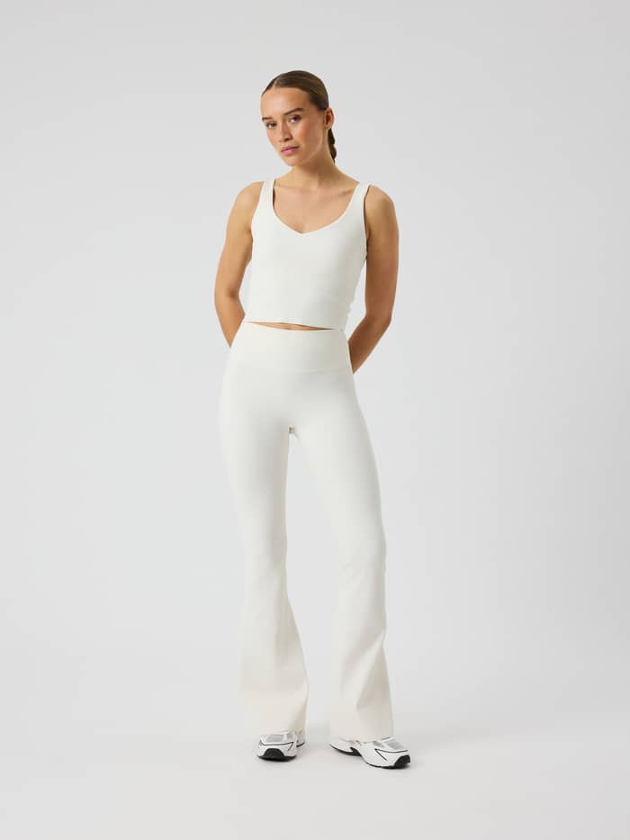 Full-body front view of a model wearing Studio Ribbed Flare Tights Regular in Tofu (White) for studio training.