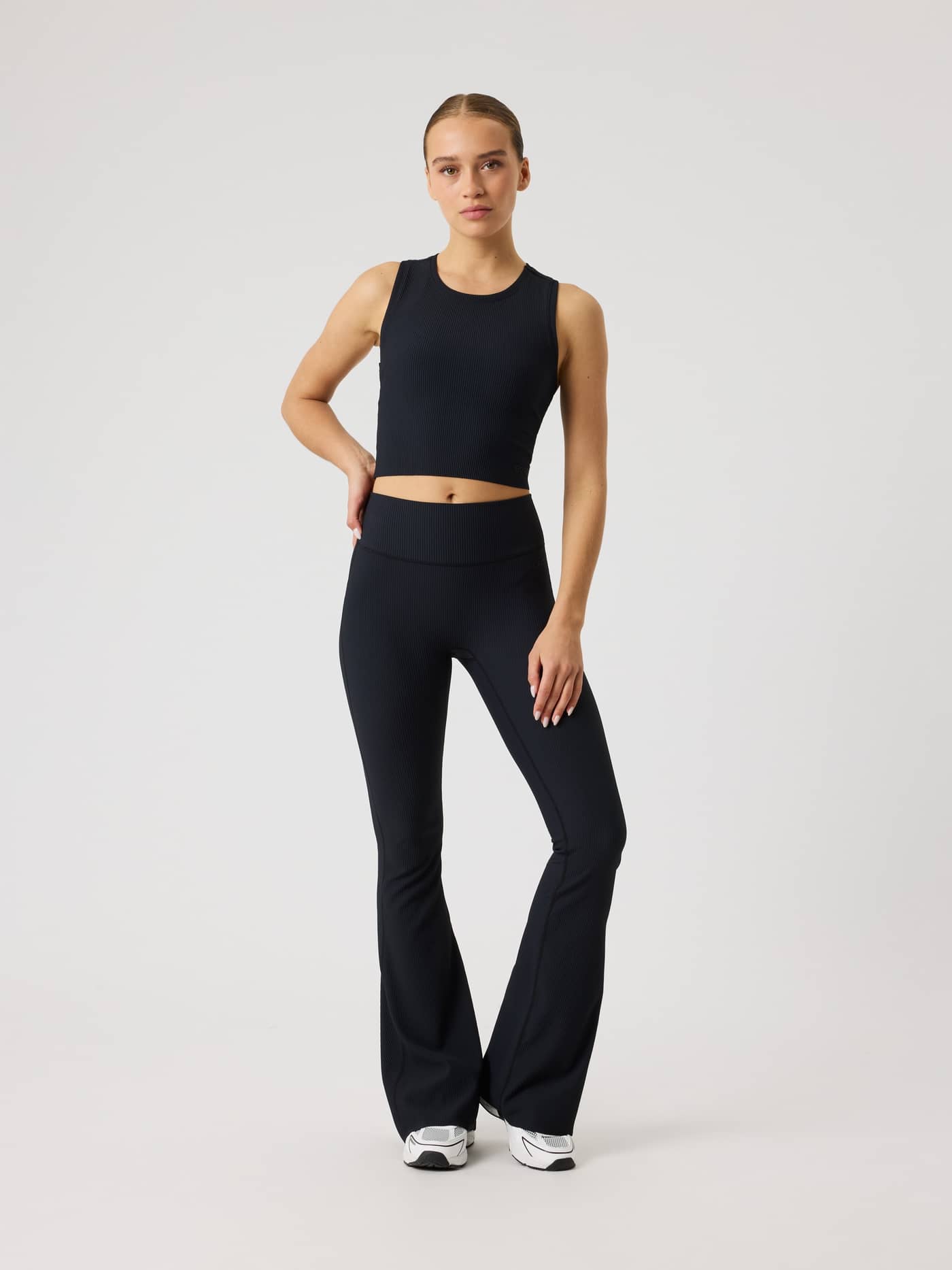 Front view of a model wearing the Studio Ribbed Flare Tights Regular in Black Beauty (Black) for training. - Image 1
