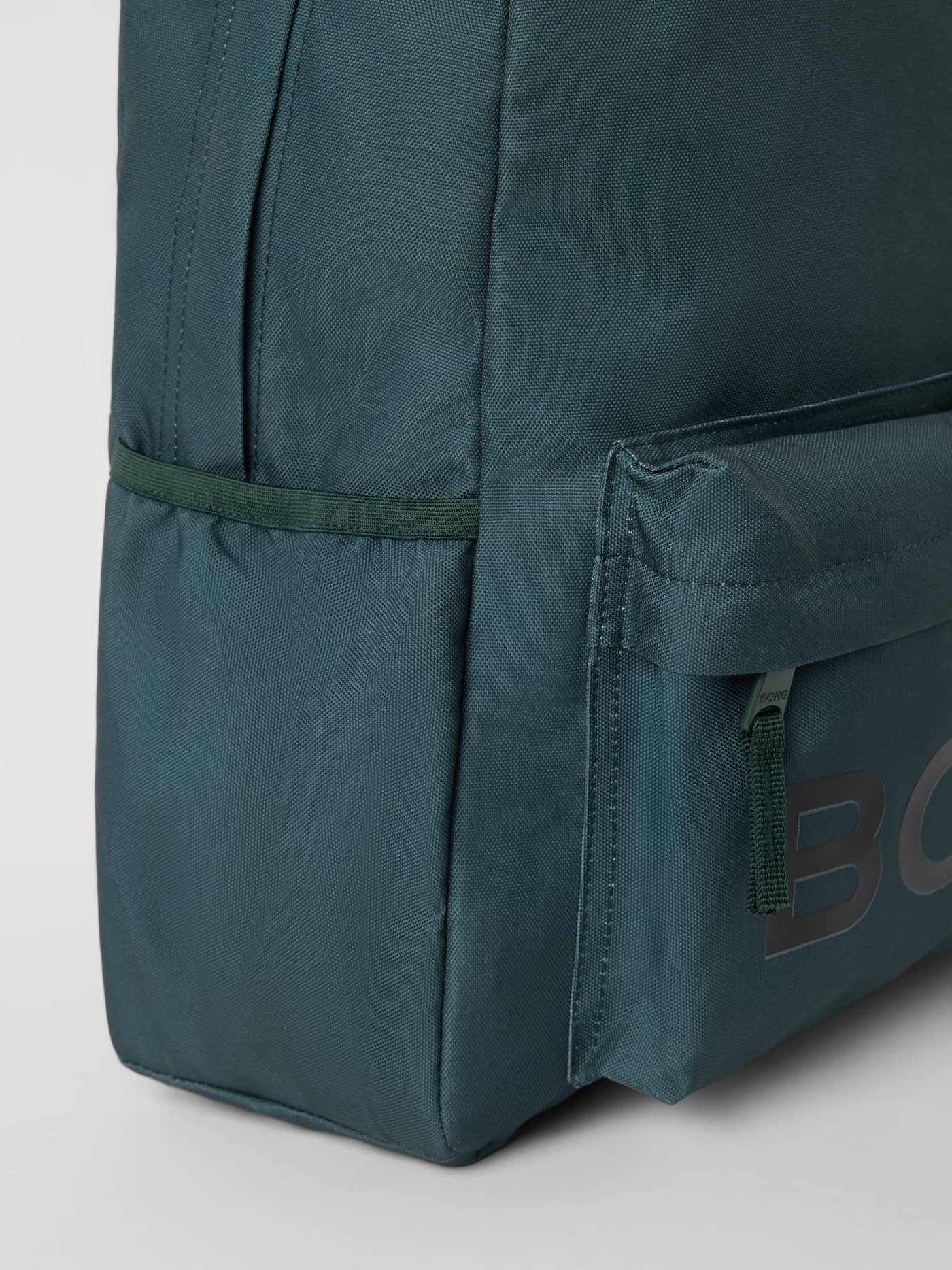 Close-up of the Mallard Green (Green) Borg Junior Backpack 15L for kids, with a printed finish, side pocket, and black logo. - Image 4