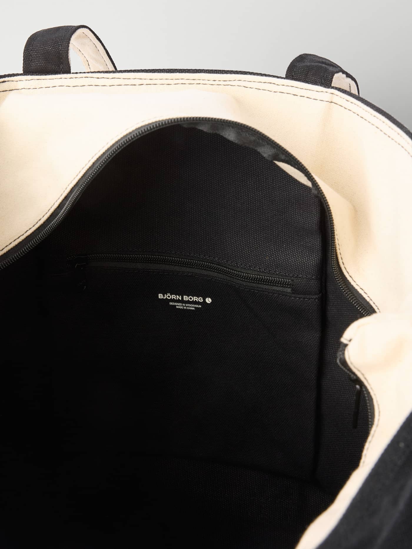 Interior of the cotton Björn Borg Ace Canvas Tote 30L in Black Beauty (Black) with a zippered tennis pocket and white logo. - Image 4