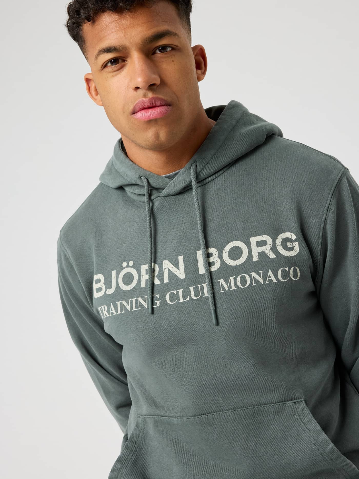 Vue de face d'un homme en Borg Classic Print Hoodie Urban Chic (Vert) à graphisme d'entraînement, idéal pour le tennis. - Image 4