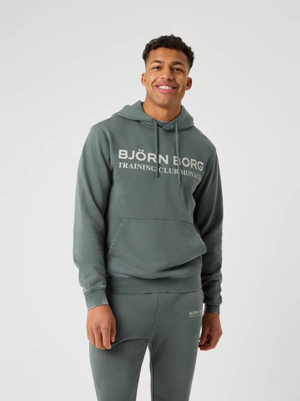 Vue de face d'un homme en Borg Classic Print Hoodie en coton Urban Chic (Vert) avec logo d'entraînement blanc cassé.