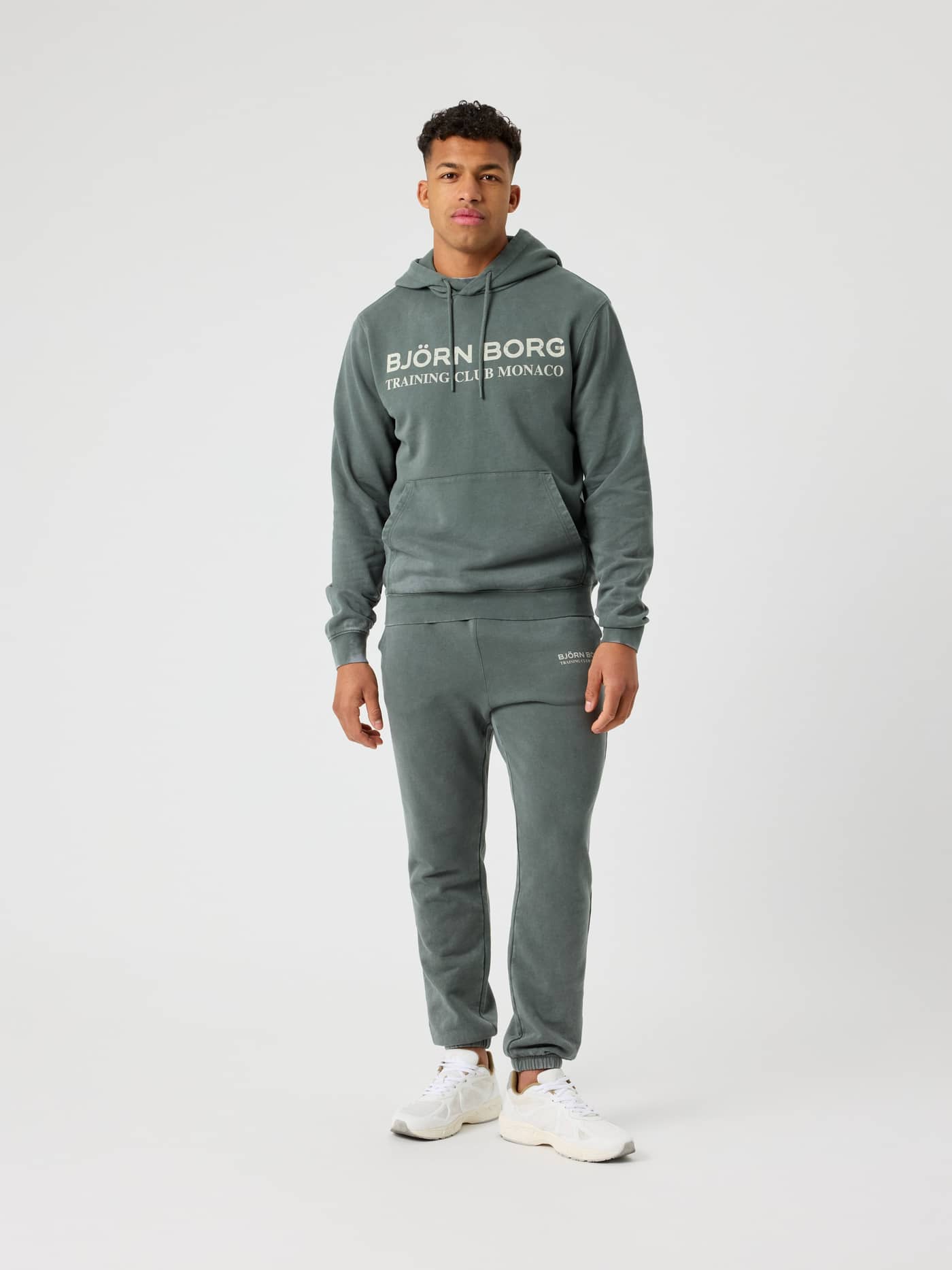 Vue de face d'un homme en Borg Classic Print Hoodie en coton Urban Chic (Vert) avec un logo de training blanc. - Image 3