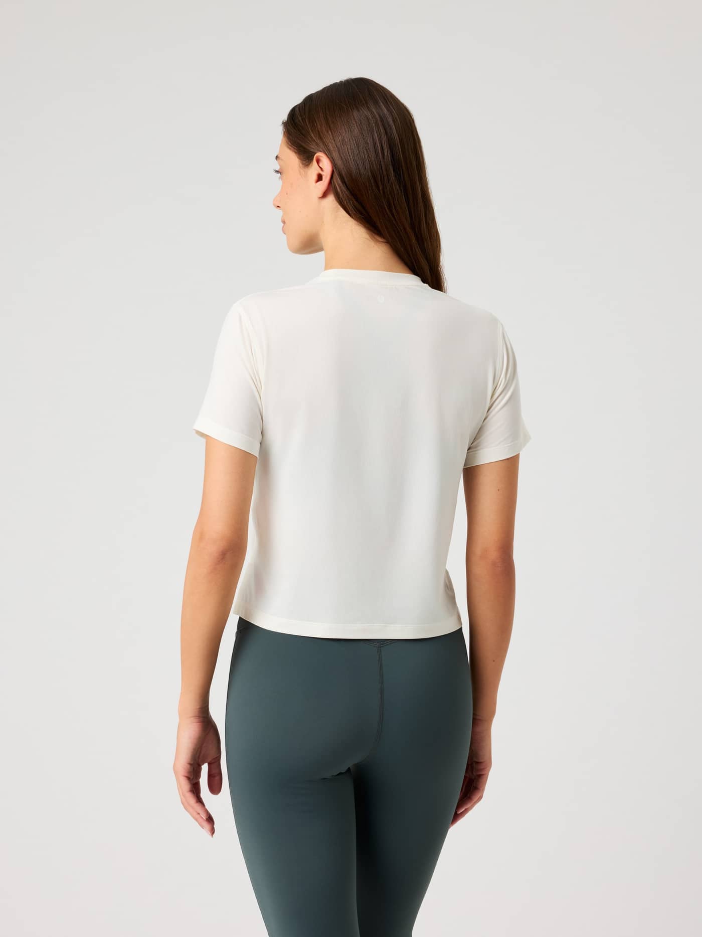 Back view of a woman wearing the Borg Cropped T-Shirt in Tofu (White), offering a stylish fit for training sessions. - Image 2