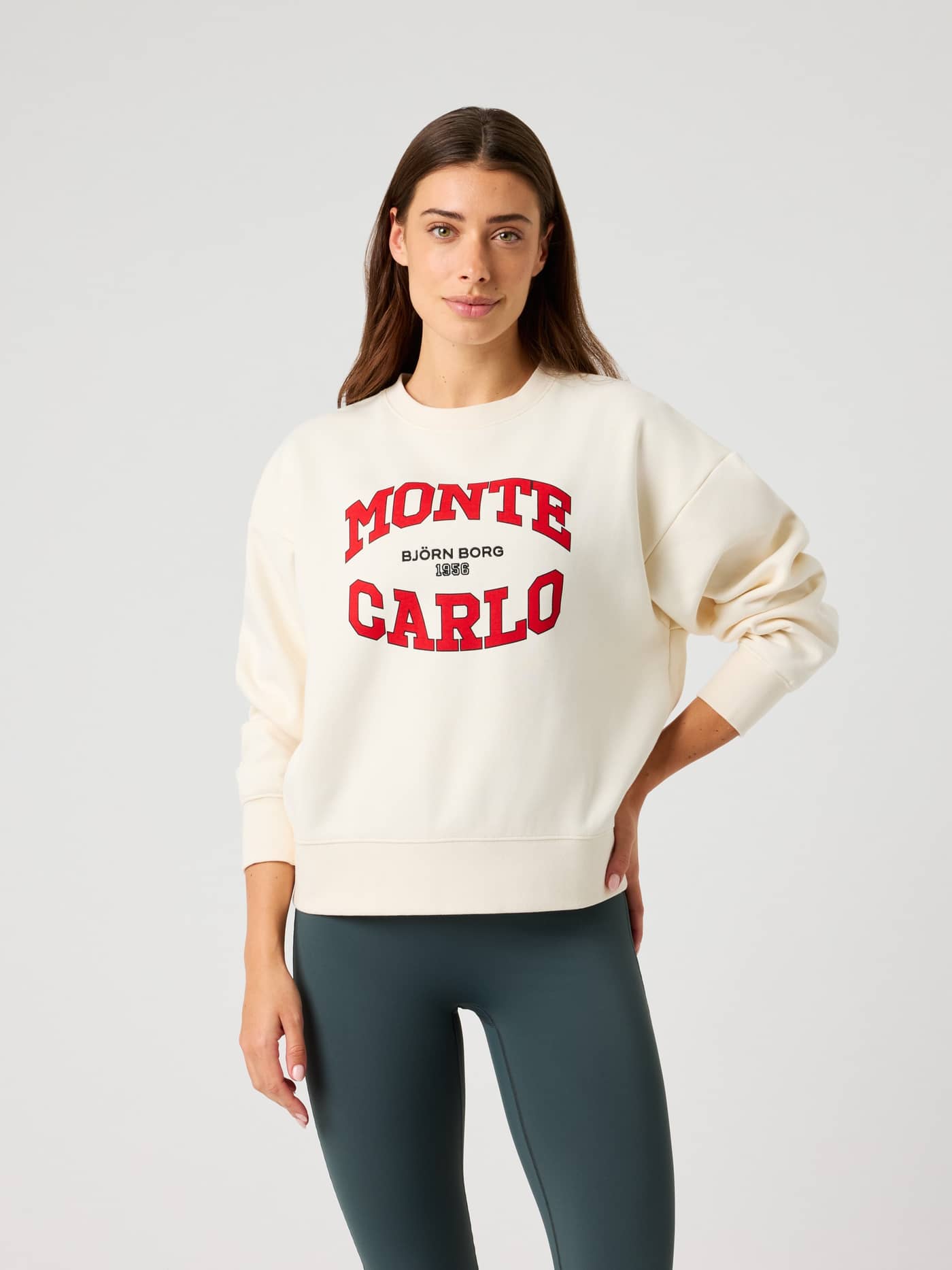 Front view of a woman in the oversized Borg Boyfriend Sweatshirt in Tofu (white) with red Monte Carlo graphics. - Image 1