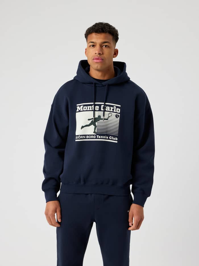 Vooraanzicht man in Borg Oversized Hoodie in Night sky (Marineblauw) met Monte Carlo tennisgraphic voor stijl en functie. - Image 2