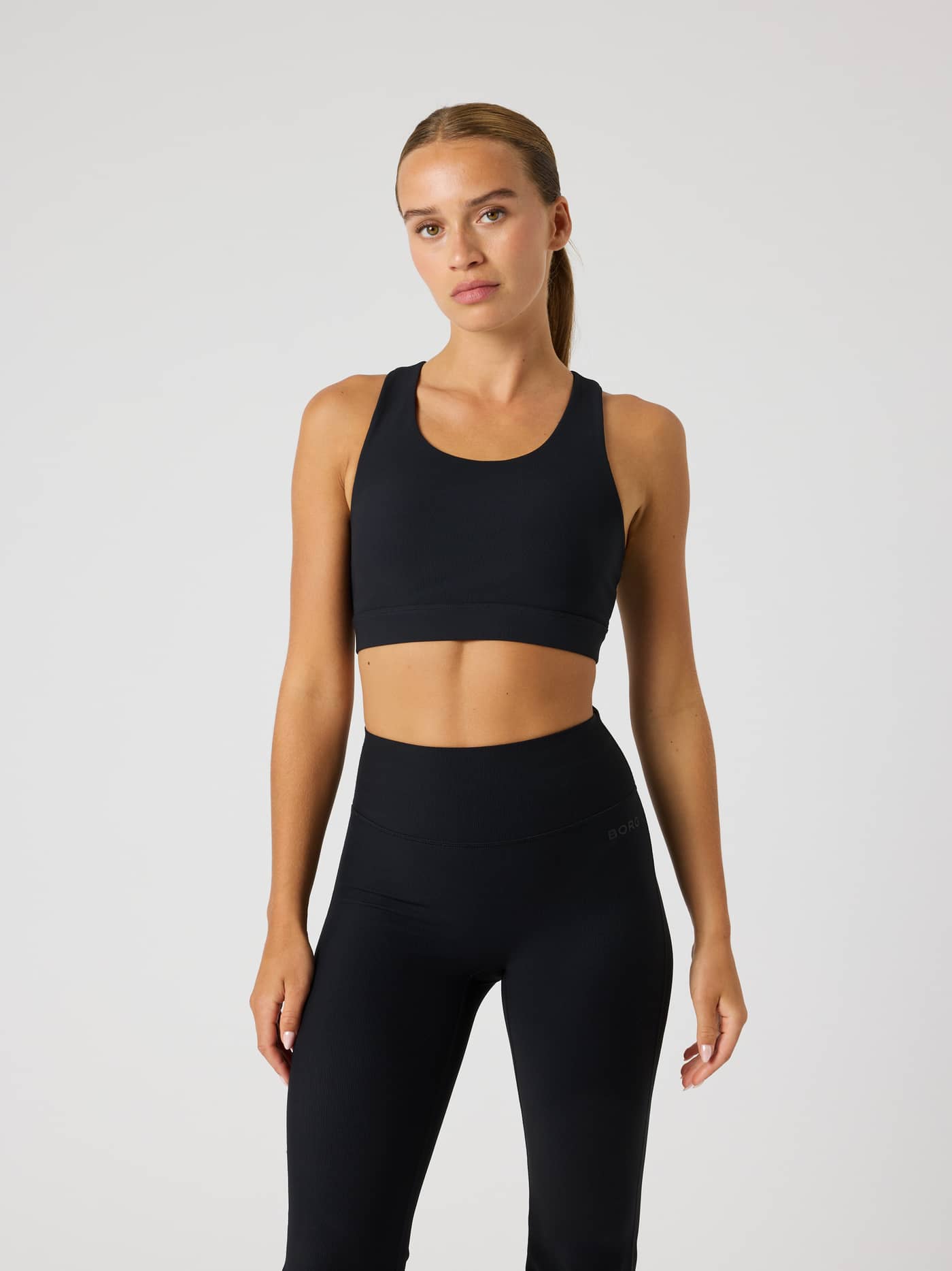 Front view of a model in the training Studio Premium Rib Sports Bra in Black Beauty (Black) with a stylish ribbed texture. - Image 1