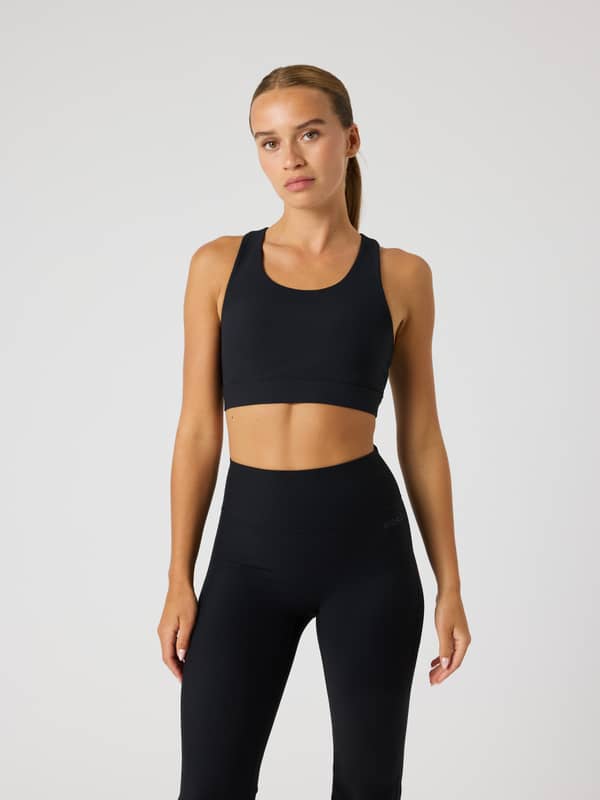 Modell framifrån i Studio Premium Rib Sports Bra i Black Beauty (Svart) med en stilfull ribbad textur för träning.