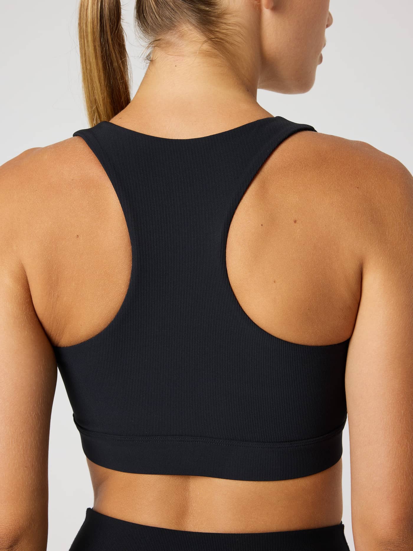 Close-up achteraanzicht van de Studio Premium Rib Sports Bra in Black Beauty (Zwart) voor training. - Image 5