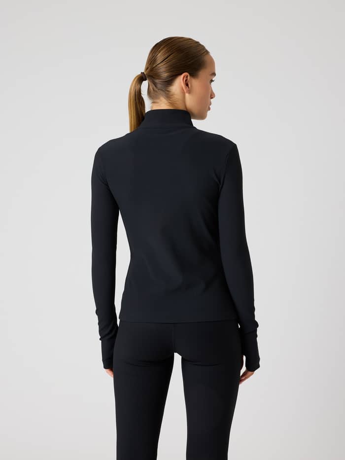 Vista posterior de una mujer con la Studio Premium Ribbed Midlayer en Black Beauty (Negro) y un ajuste de entrenamiento.