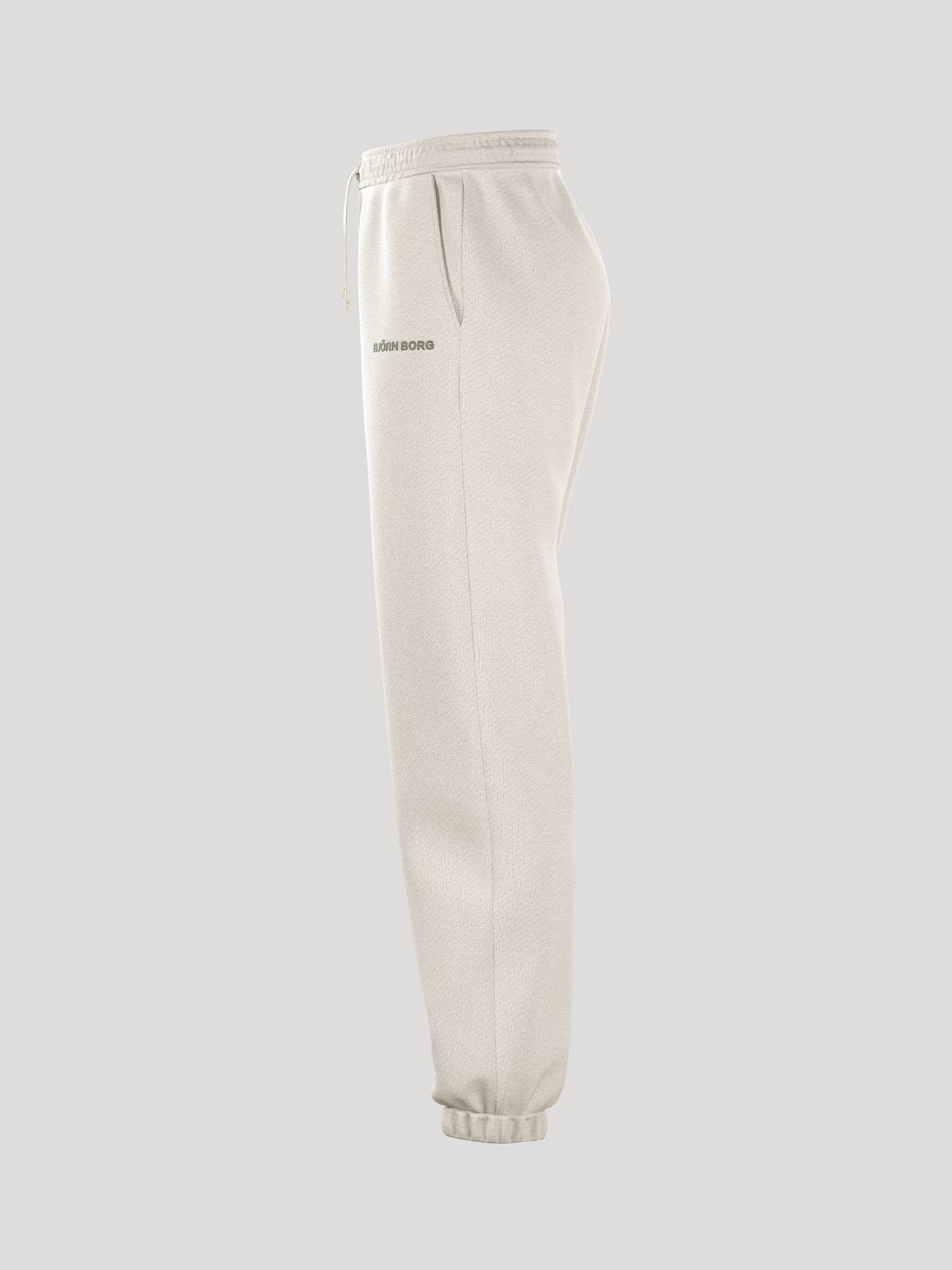Side view of the loose-fitting Borg Essential 4 Sweatpants in Tofu (White) featuring a grey logo and ribbed cuffs. - Image 4