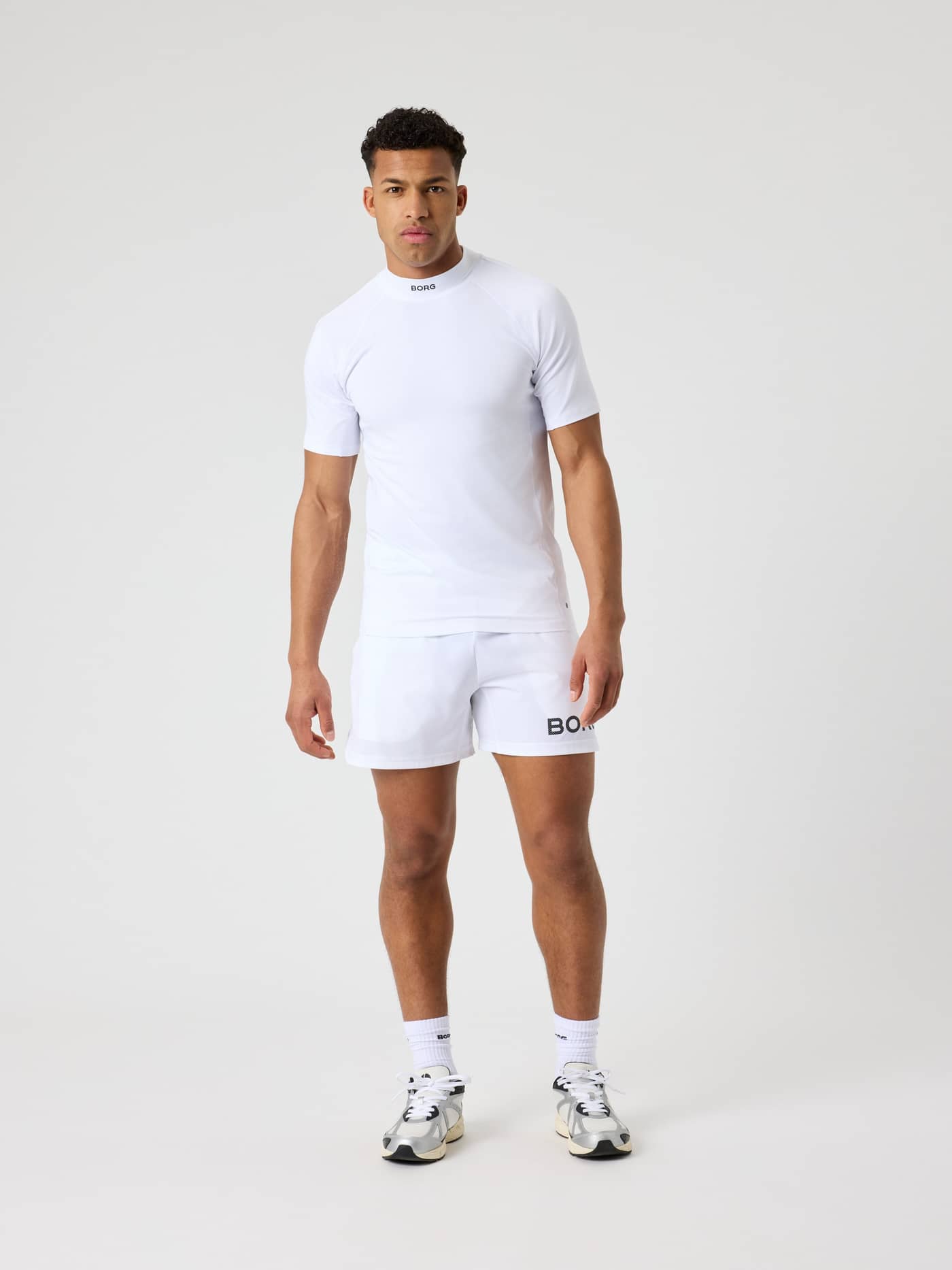 Full-body front view of a man wearing the Brilliant White (White) Borg Mock Neck T-Shirt with black logos for tennis. - Image 3