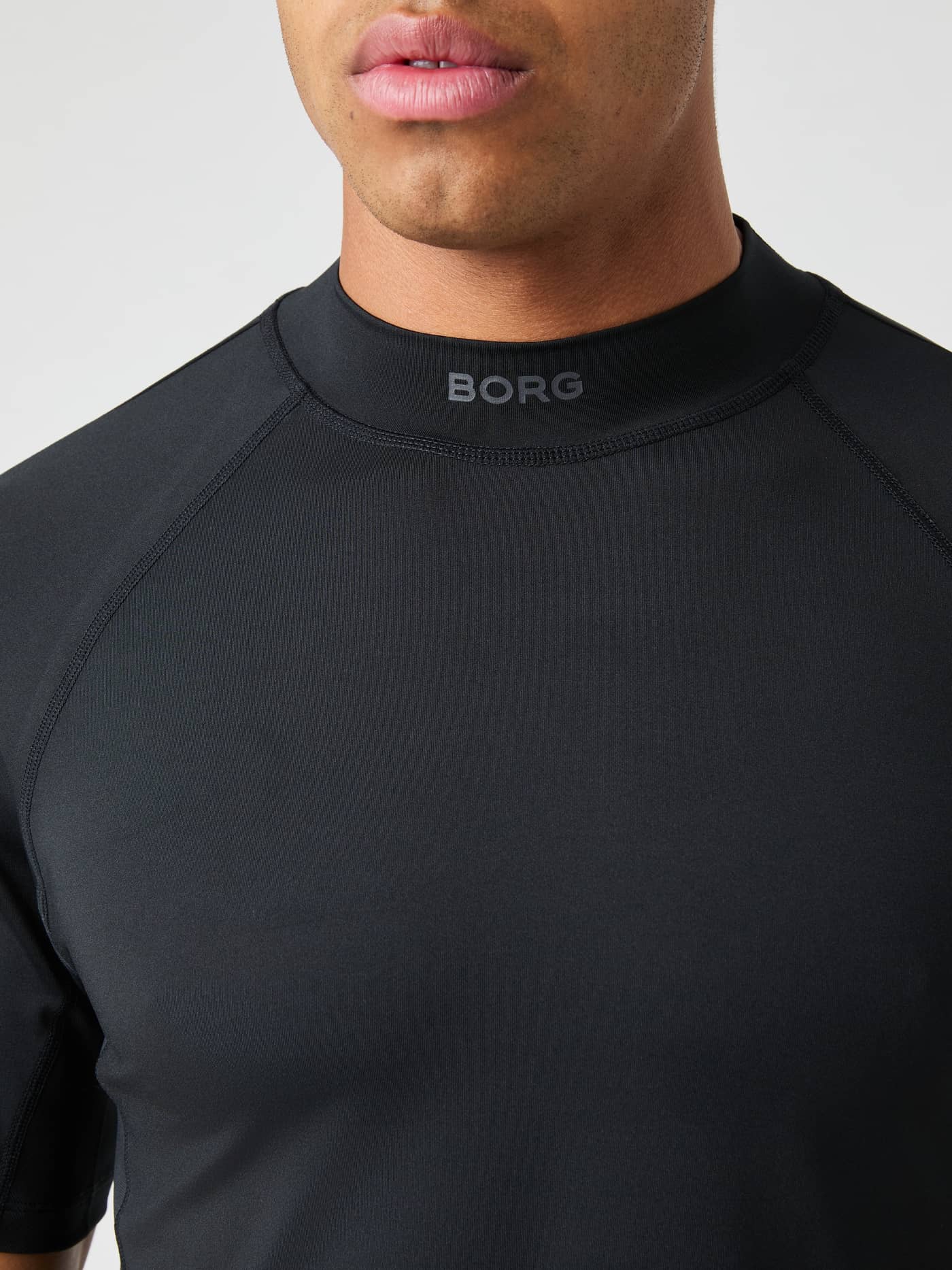Front close-up of the Björn Borg Mock Neck T-Shirt in Black Beauty (Black) with a grey logo for tennis performance. - Image 6