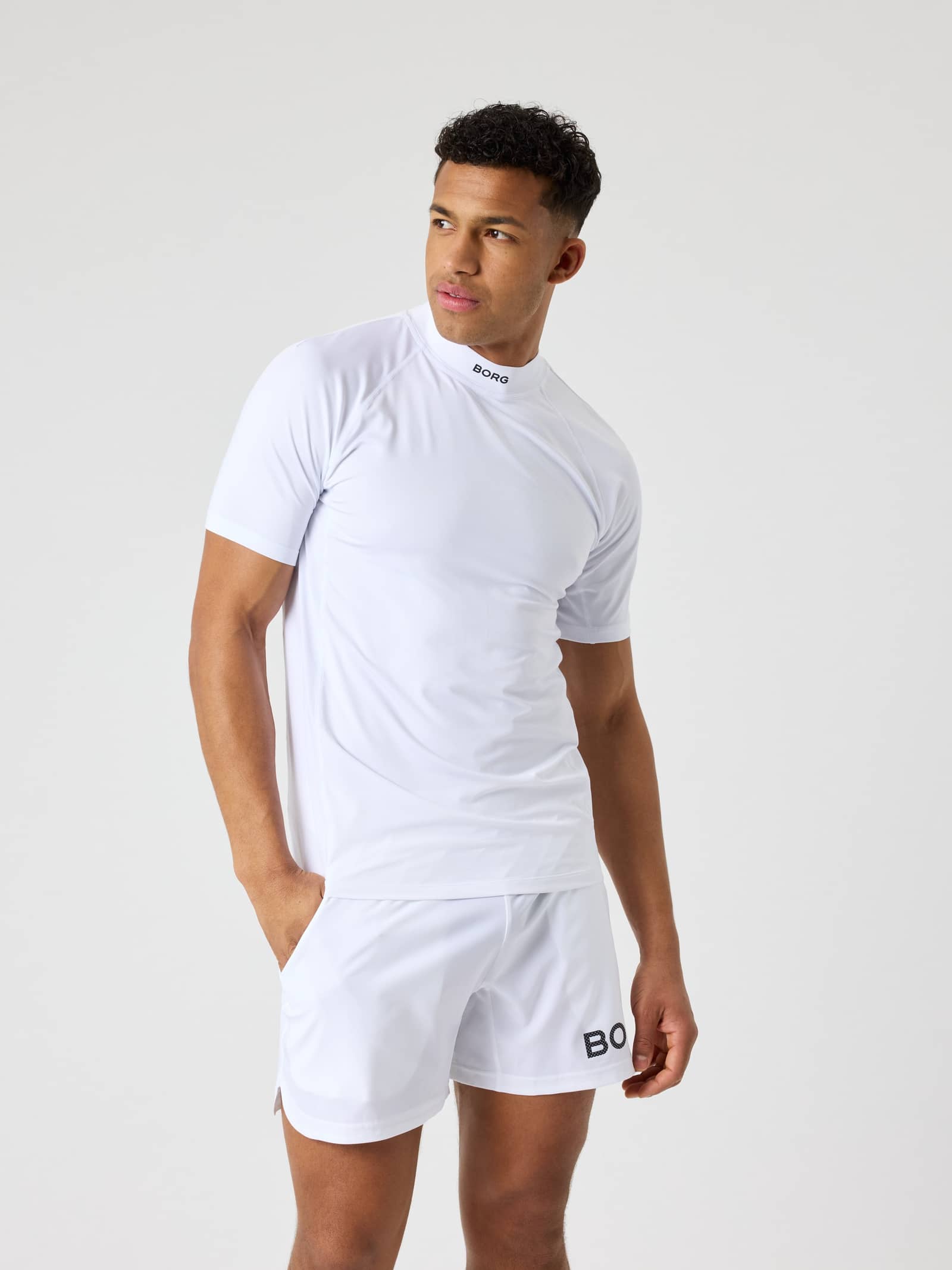 Front view of a man in the Borg Mock Neck T-Shirt in Brilliant White (White), a performance top for tennis training. - Image 1