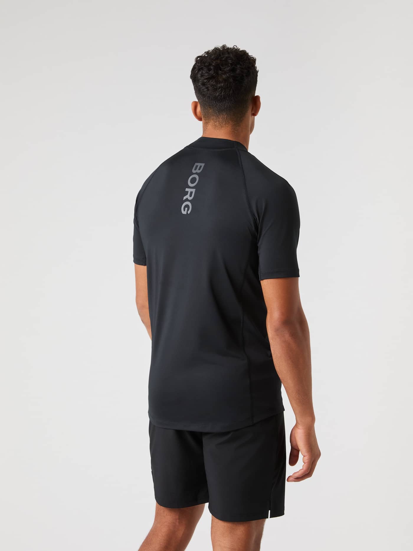 Back view of a man wearing the Björn Borg Mock Neck T-Shirt in Black Beauty (Black) with a grey logo for tennis performance. - Image 2