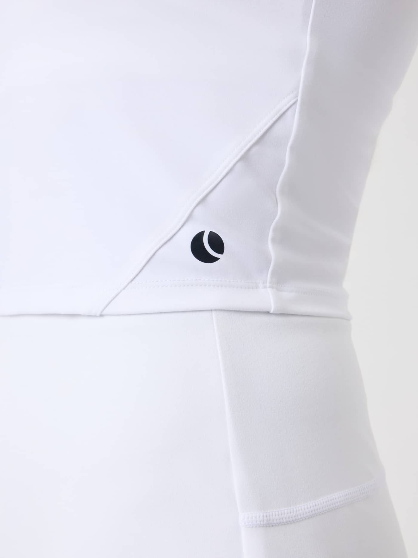 Close-up of the Ace 2 In 1 Cropped Tank in Brilliant White (White) featuring a black tennis logo and performance stretch. - Image 5