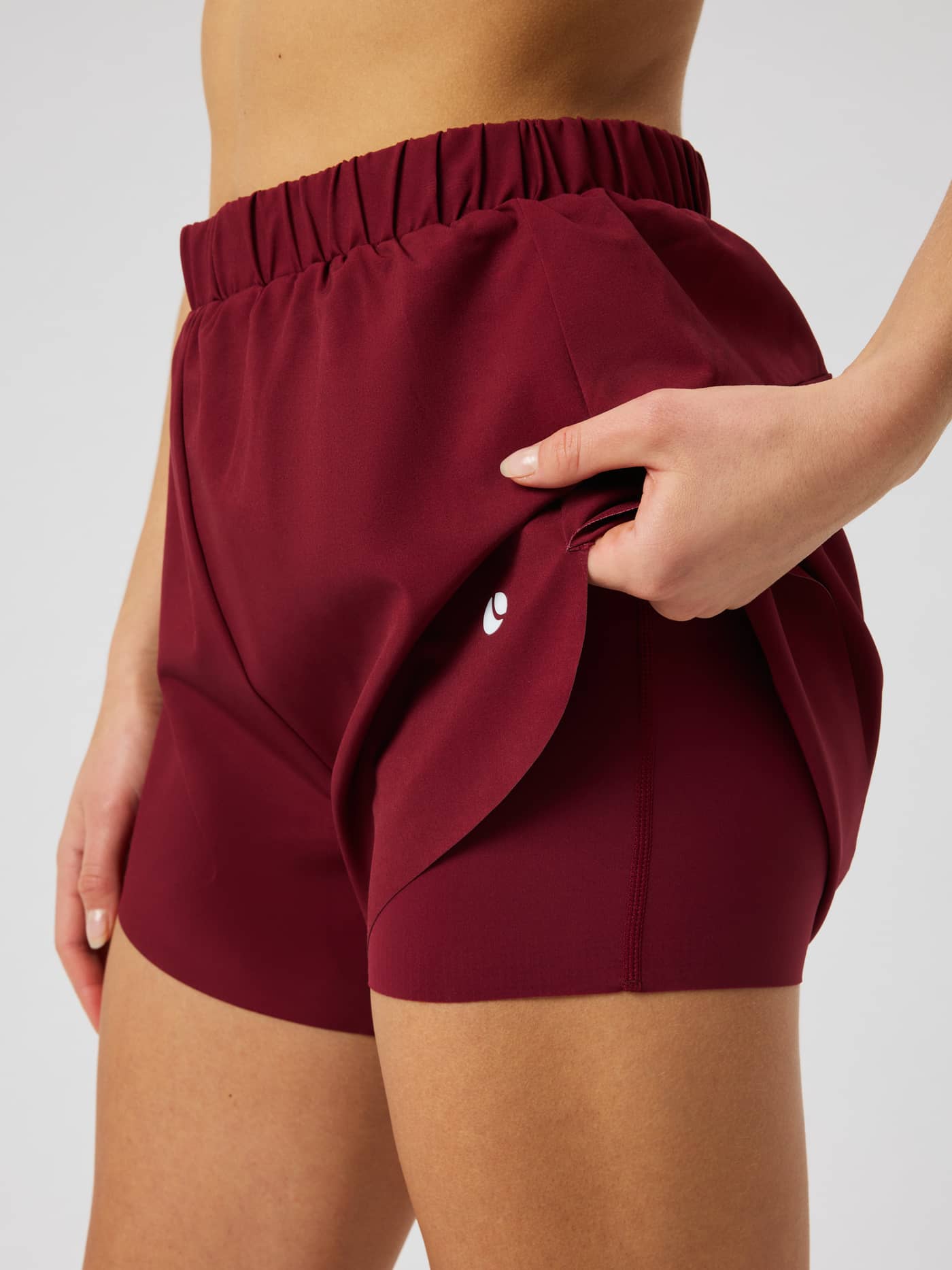 Close-up of the Ace 2 In 1 Shorts in Cabernet (Red), highlighting the dual-layer design and white logo. - Image 4
