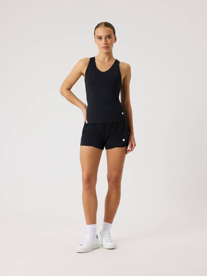 Full-body front view of a woman wearing the Ace 2 In 1 Shorts in Black Beauty (Black) for tennis and padel. - Image 3