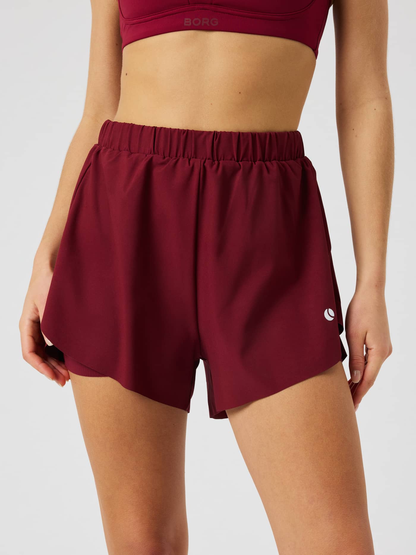 Front view of the Ace 2 In 1 Shorts in Cabernet (Red) for tennis featuring an elastic waistband and side slits. - Image 2