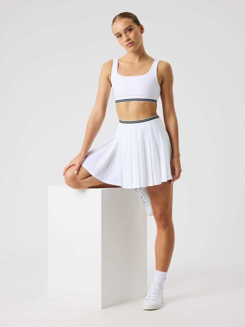 Full-body front view of a model in the Björn Borg Ace Pleated Skirt in Brilliant White (White) for tennis performance.