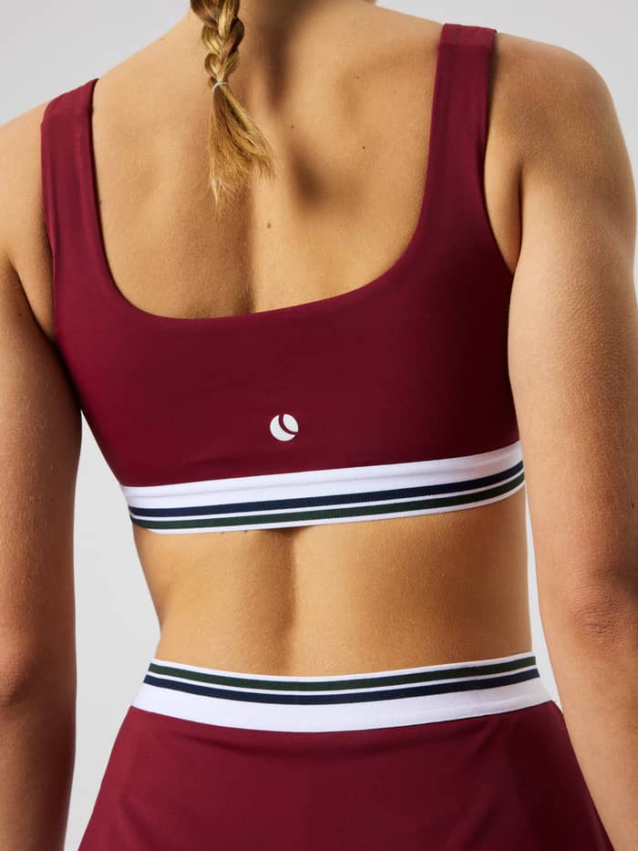 Back view of the Ace Court Top in Cabernet (Burgundy) for tennis, featuring a white logo and elastic striped waistband.