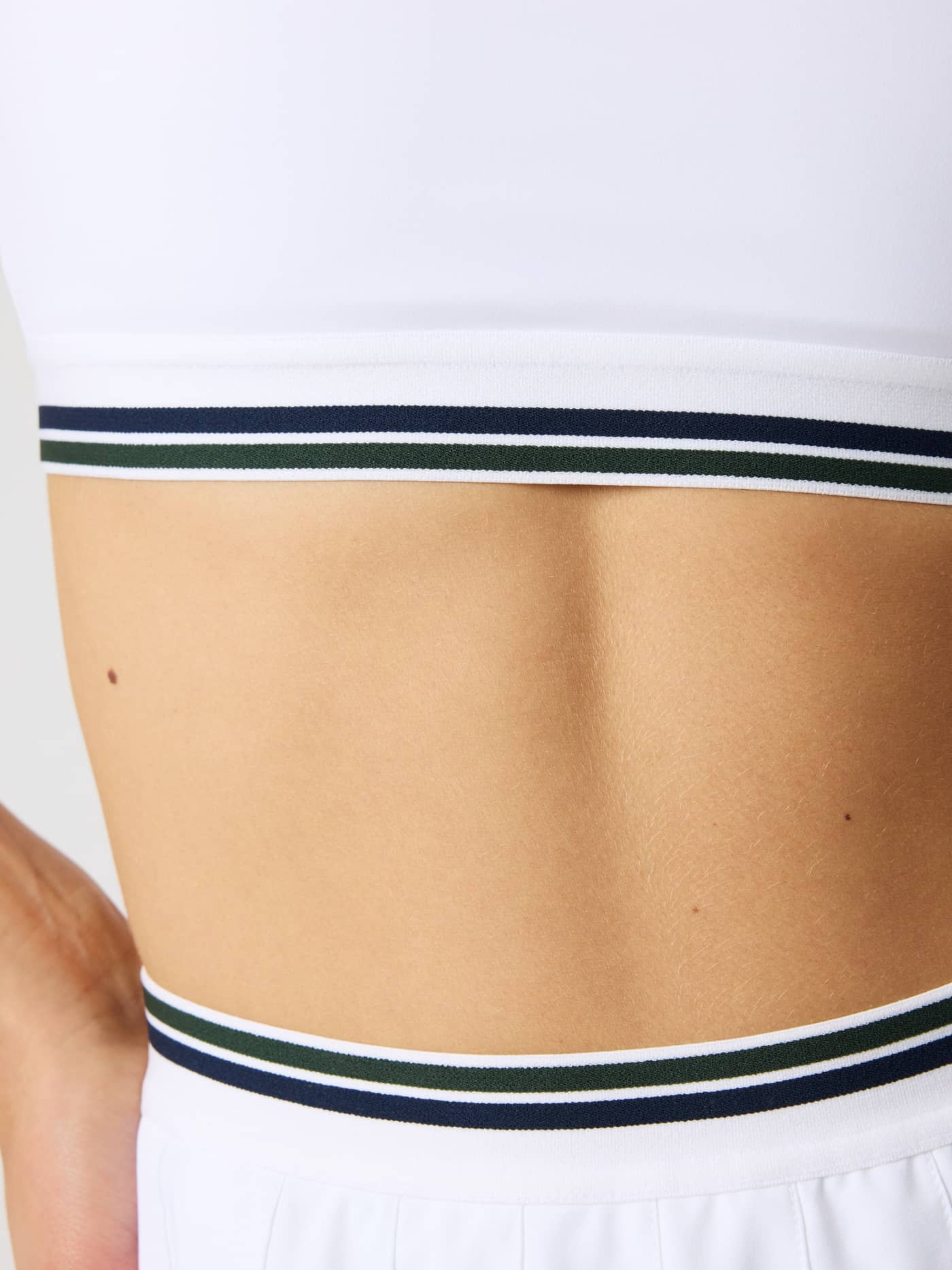Close-up of the striped elastic waistband on the Ace Court Top in Brilliant White (White) for tennis performance. - Image 7